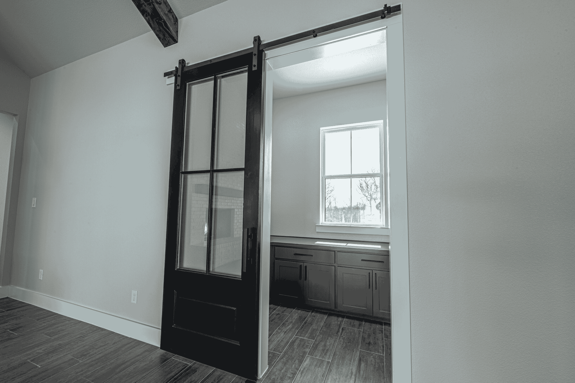 A black and white photo of a sliding barn door leading to a kitchen.
