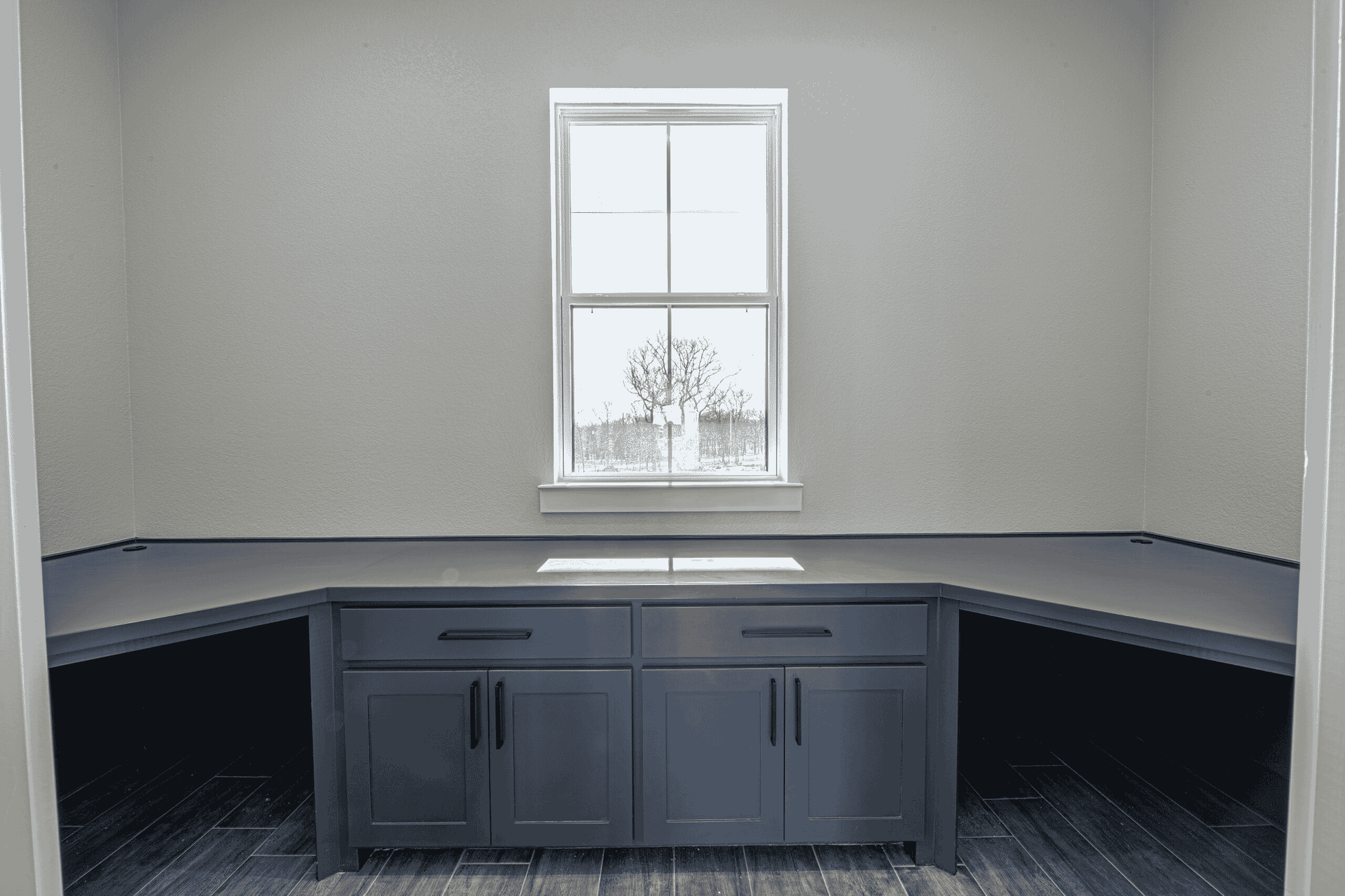 A room with a window , cabinets , and a desk.