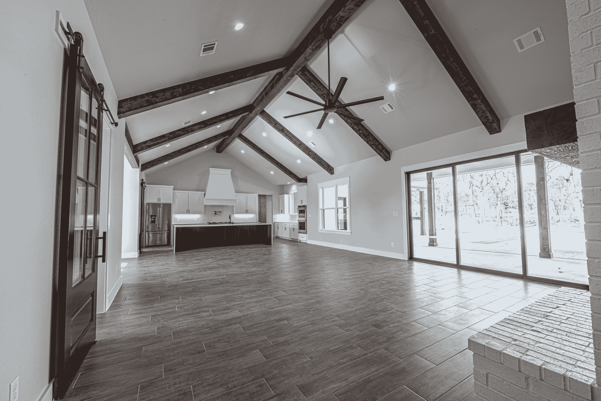 A black and white photo of an empty house with a vaulted ceiling.