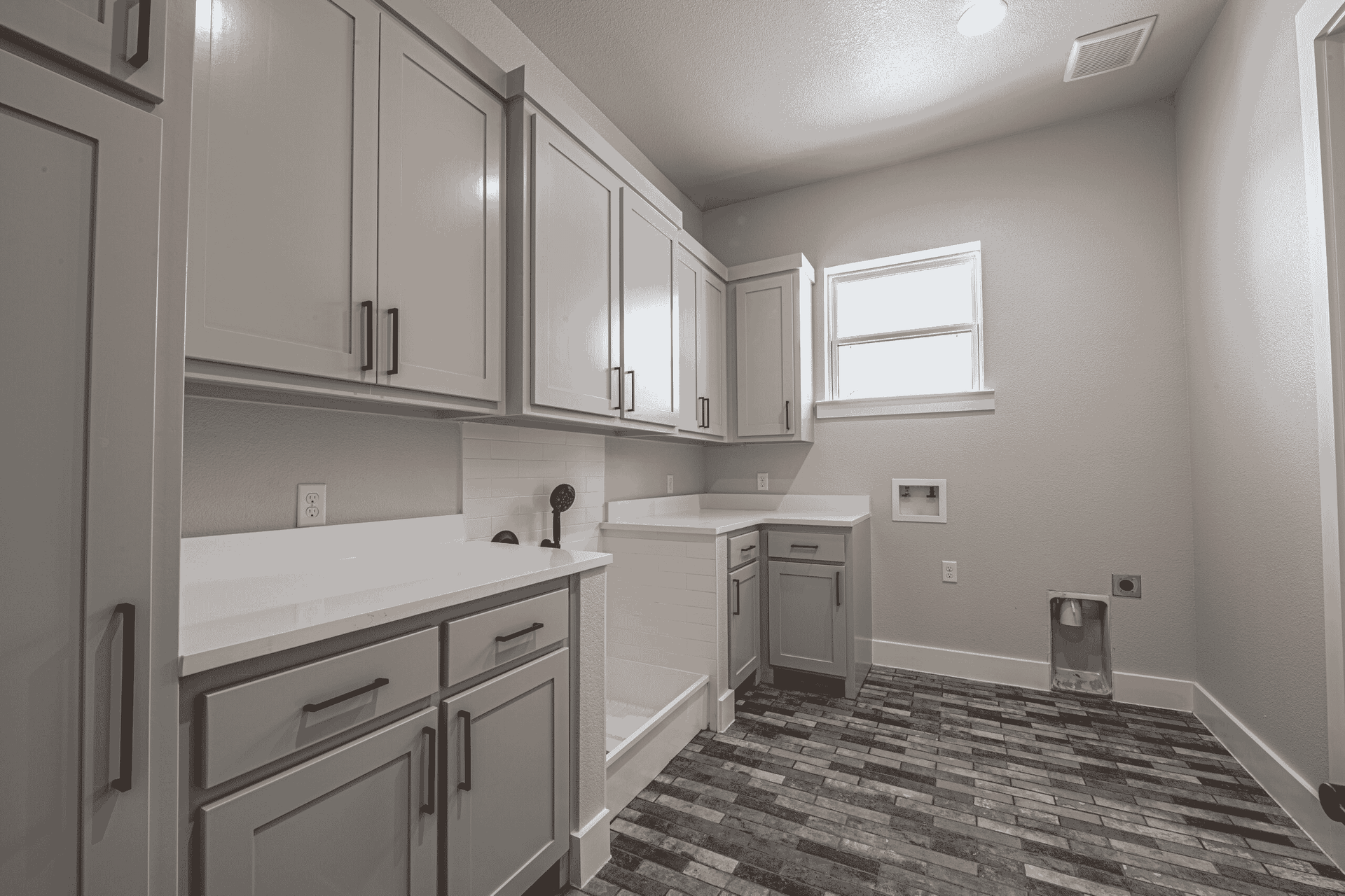 A black and white photo of a laundry room in a house.