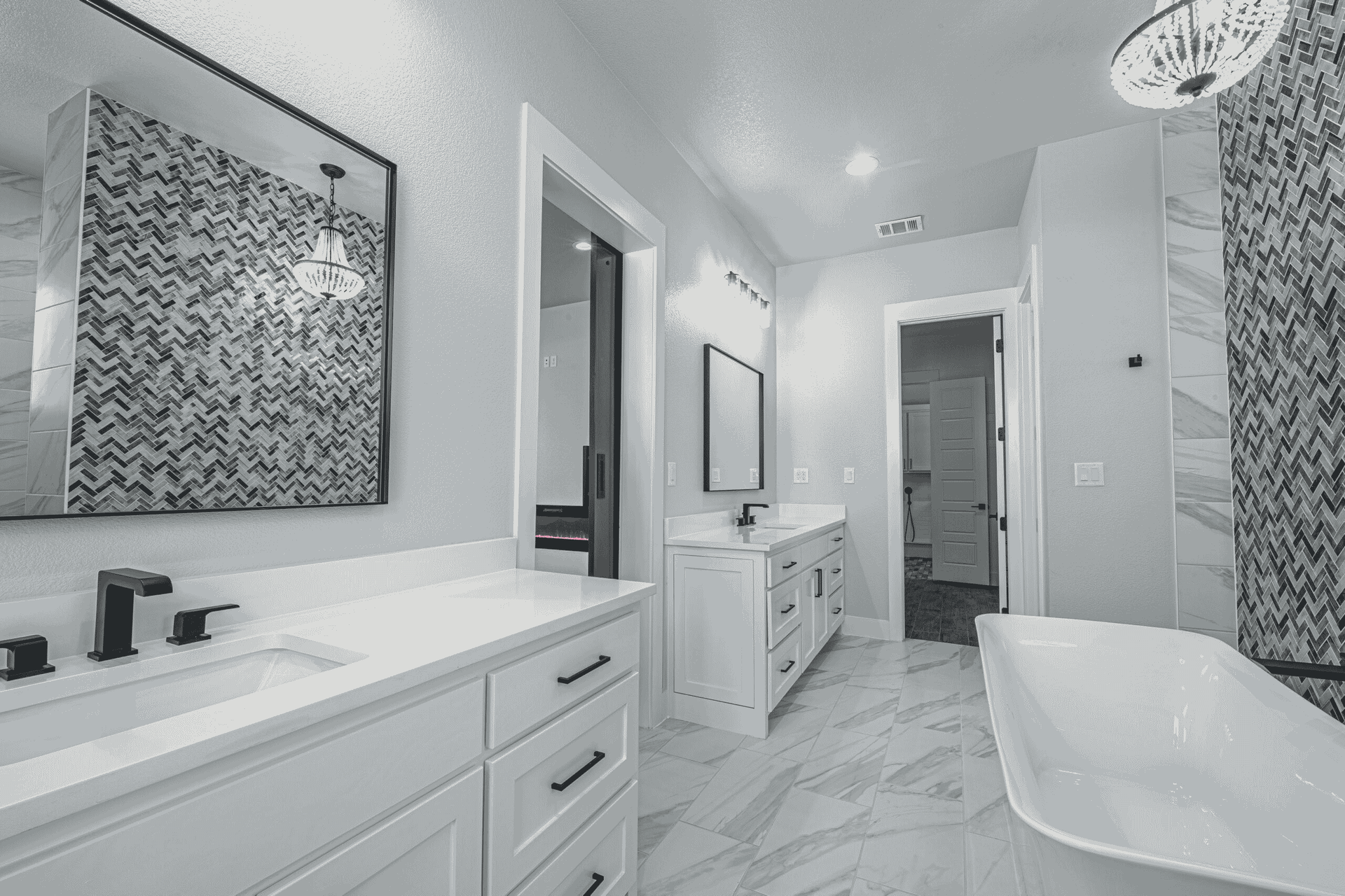 A bathroom with two sinks , a tub , a mirror and a chandelier.