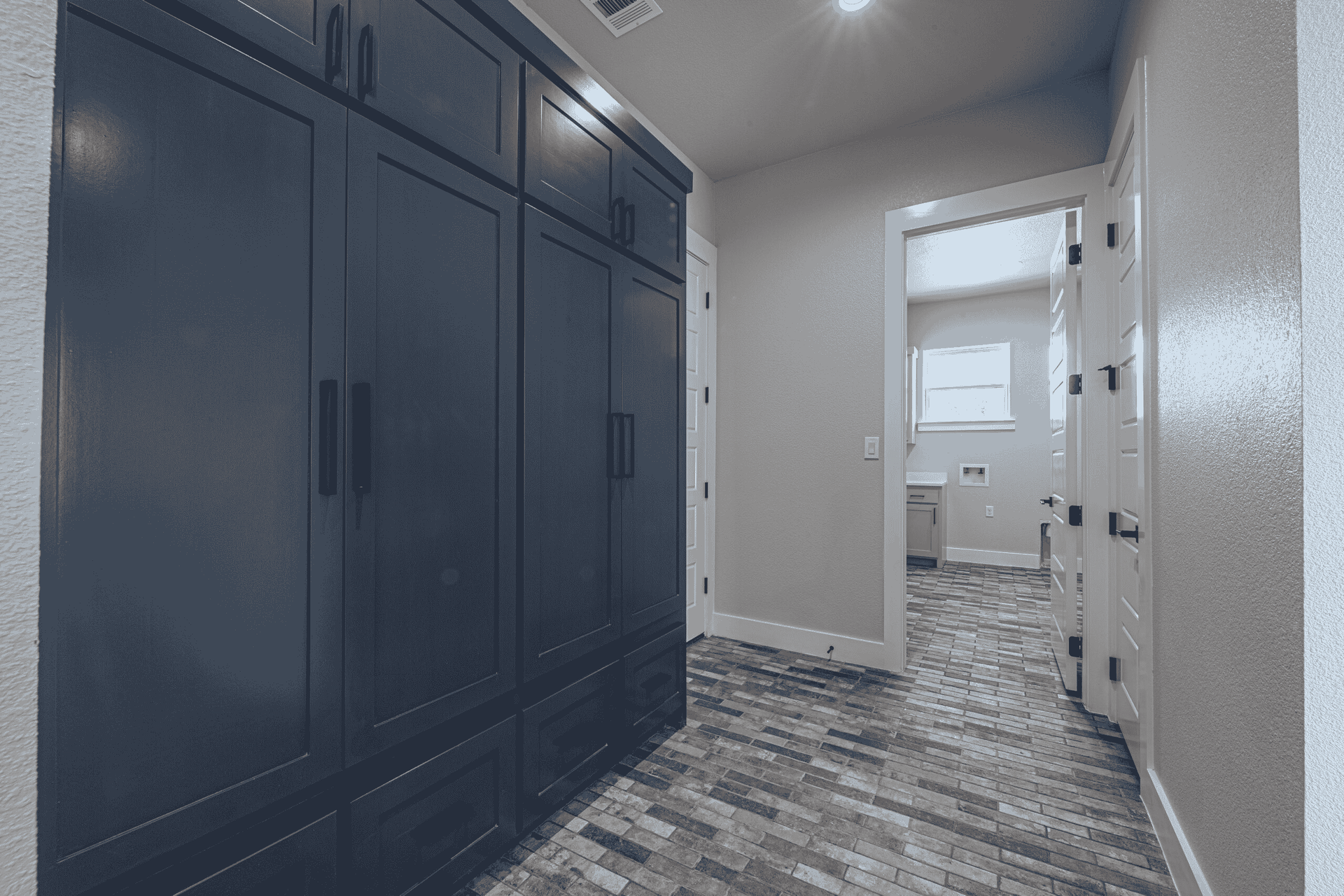 A hallway with a lot of cabinets and a bathroom in the background.