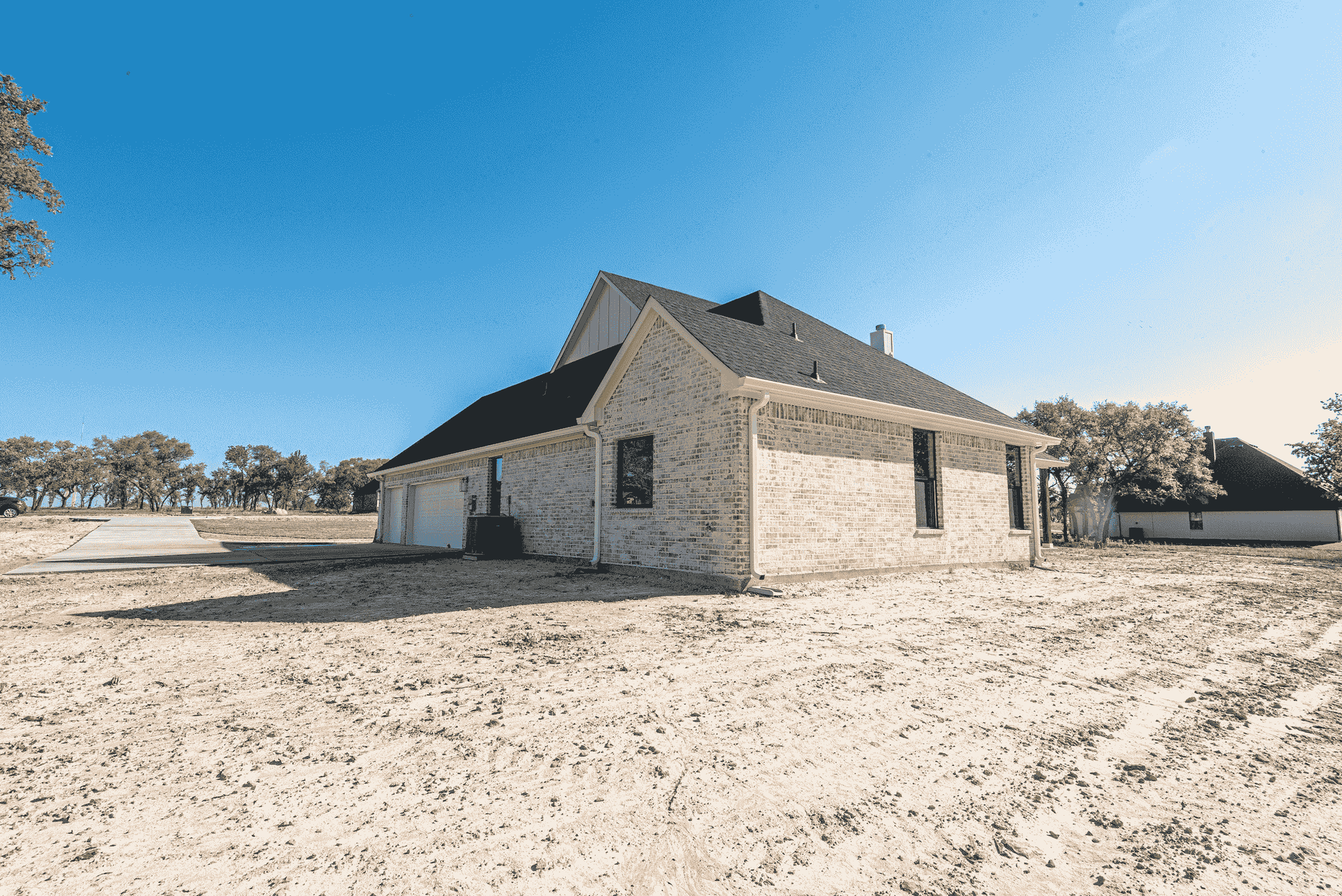 A house is sitting in the middle of a dirt field.