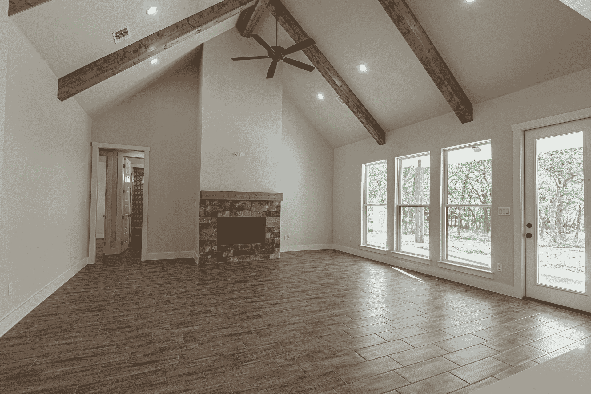 An empty living room with a fireplace and a ceiling fan.