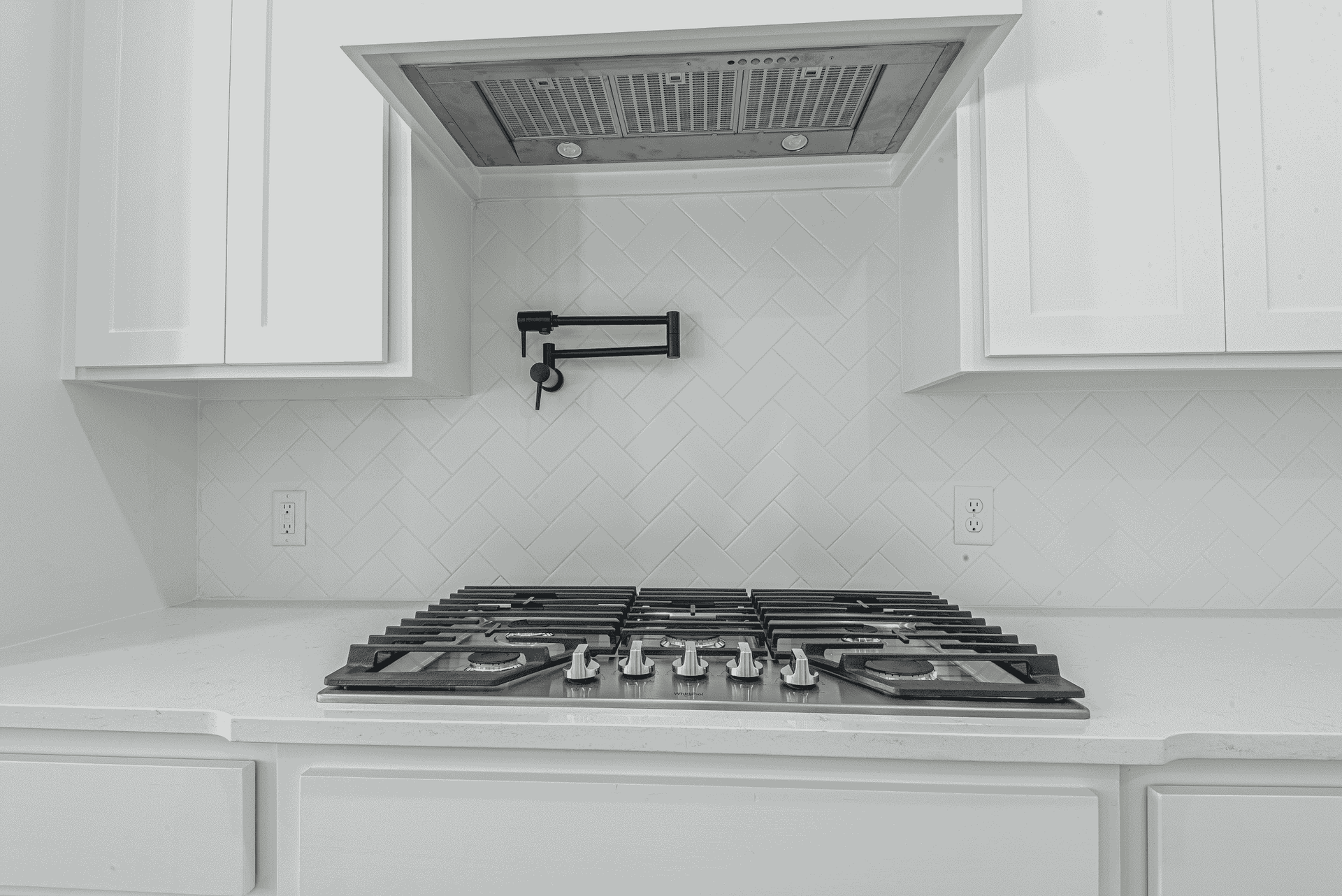 A black and white photo of a stove top oven in a kitchen.