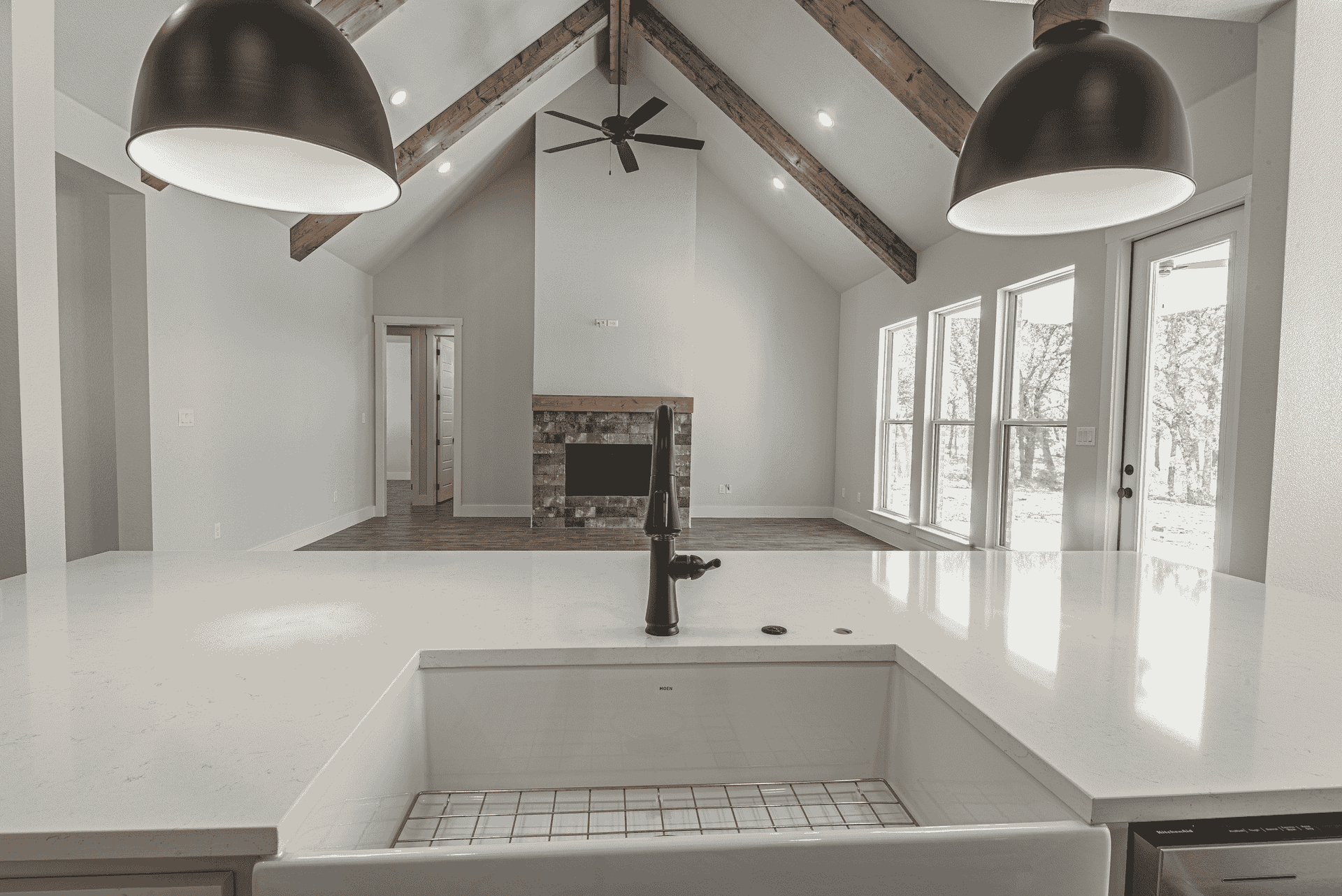 A kitchen with a sink and a fireplace in the background.