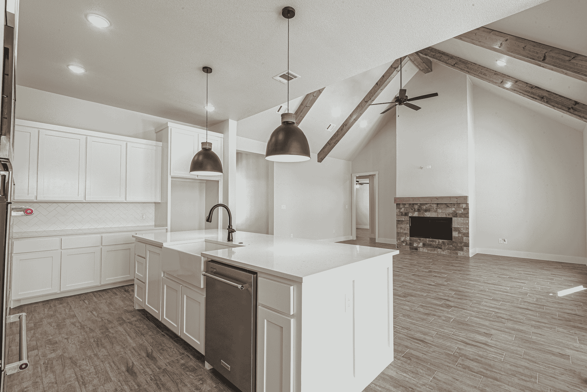 A black and white photo of a kitchen with white cabinets and a large island.