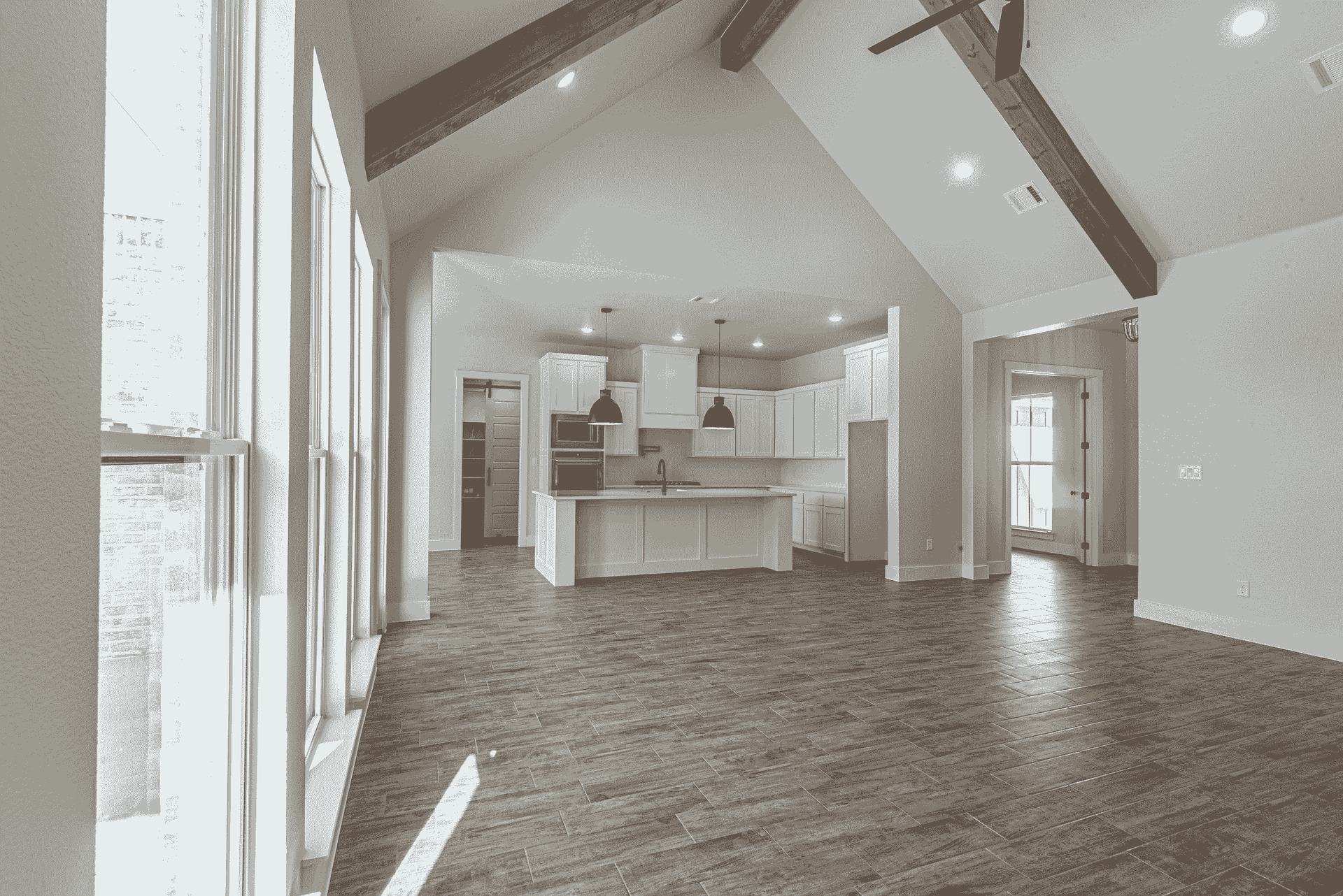 A black and white photo of an empty house with a vaulted ceiling.