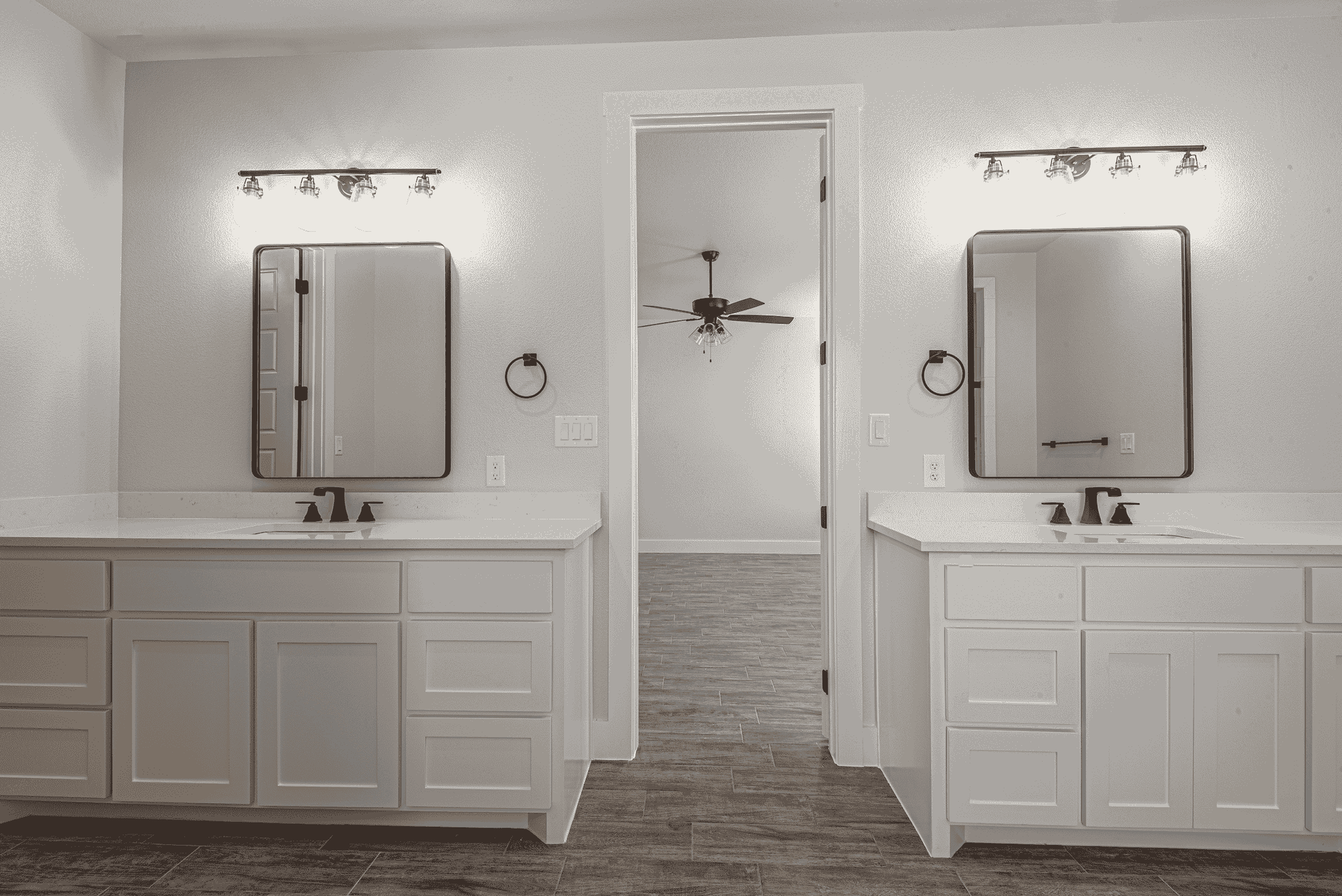 A black and white photo of a bathroom with two sinks and two mirrors.
