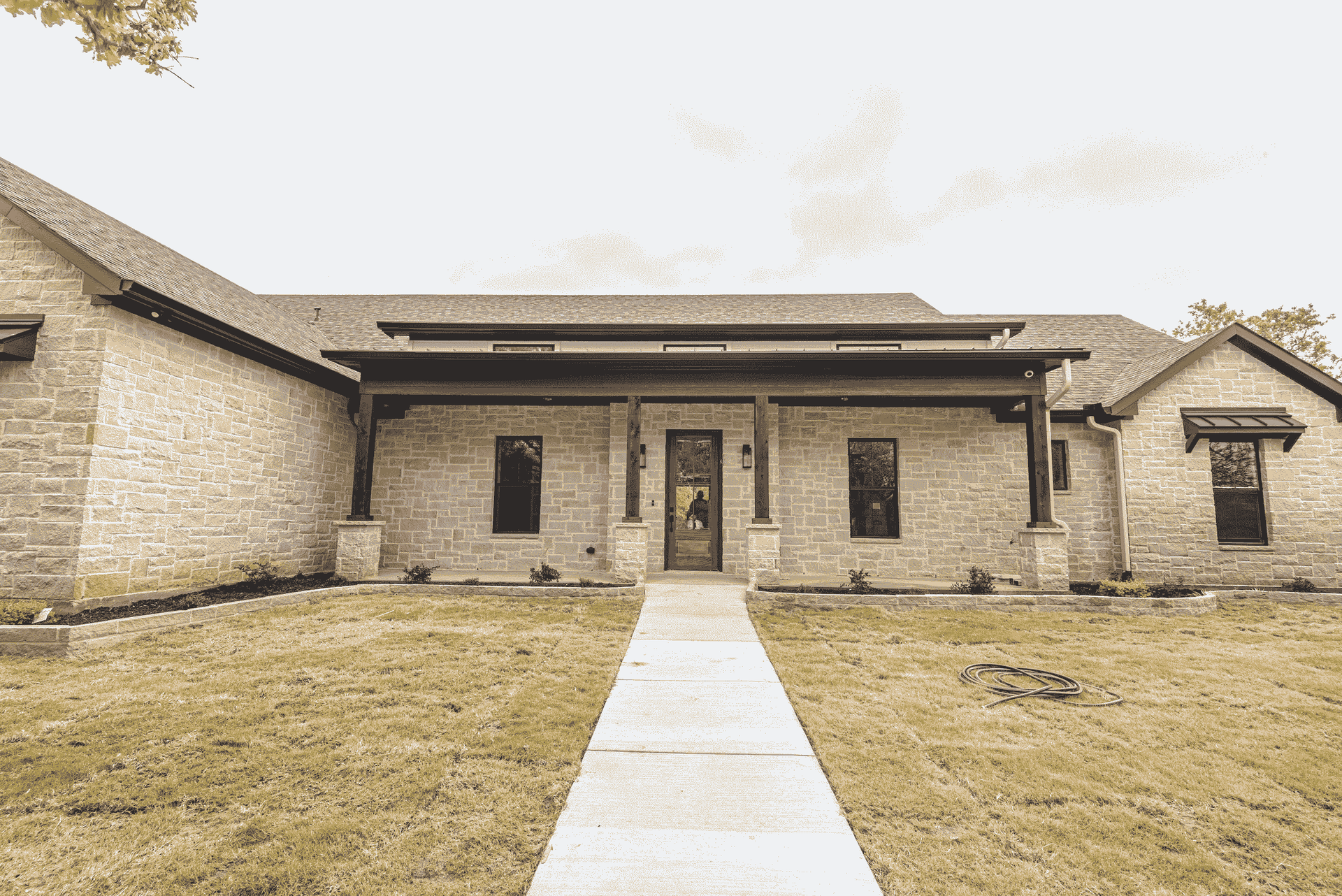 A large brick house with a concrete walkway leading to the front door.