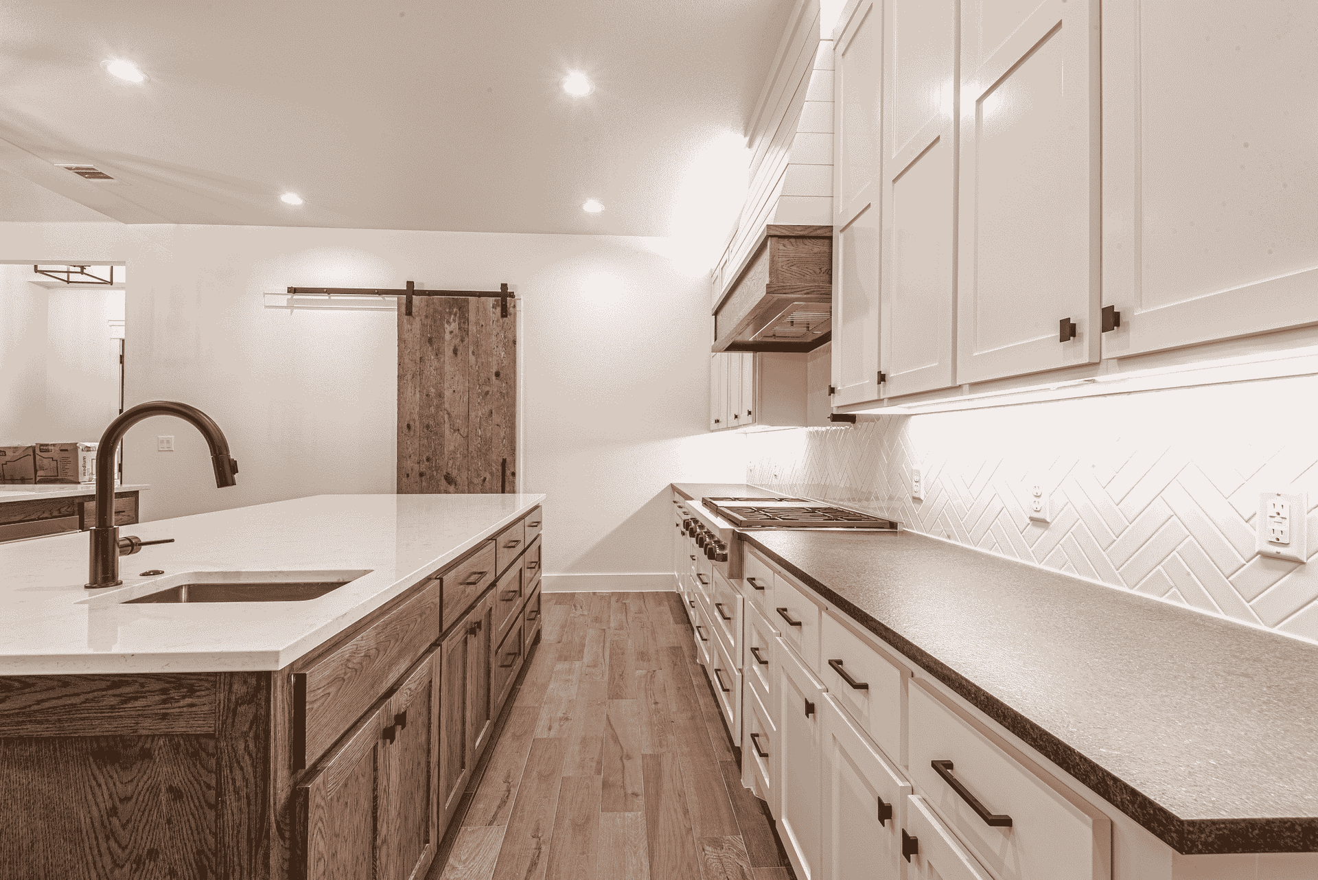 A kitchen with white cabinets , granite counter tops , a sink , and a sliding barn door.