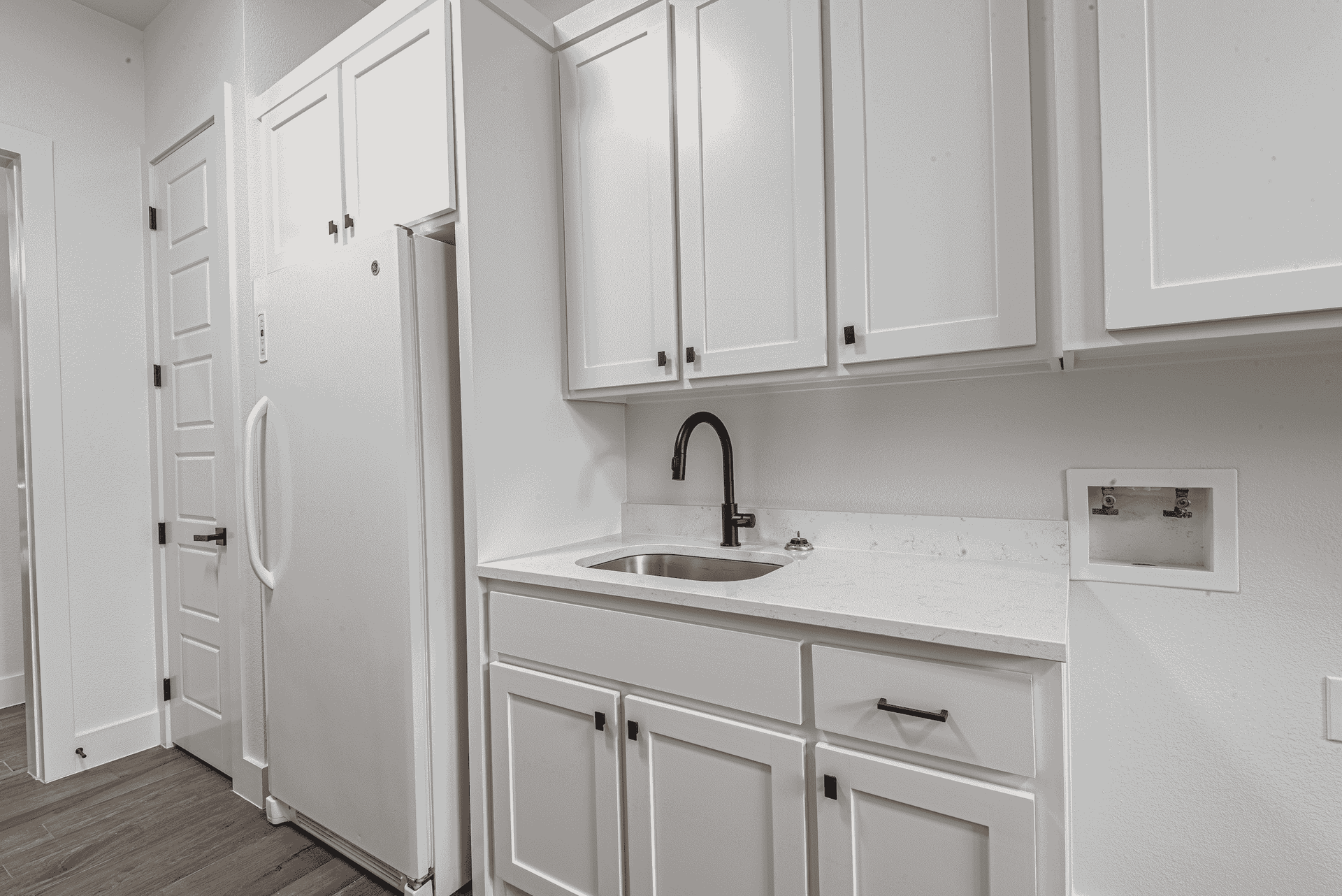A kitchen with white cabinets , a sink , and a refrigerator.