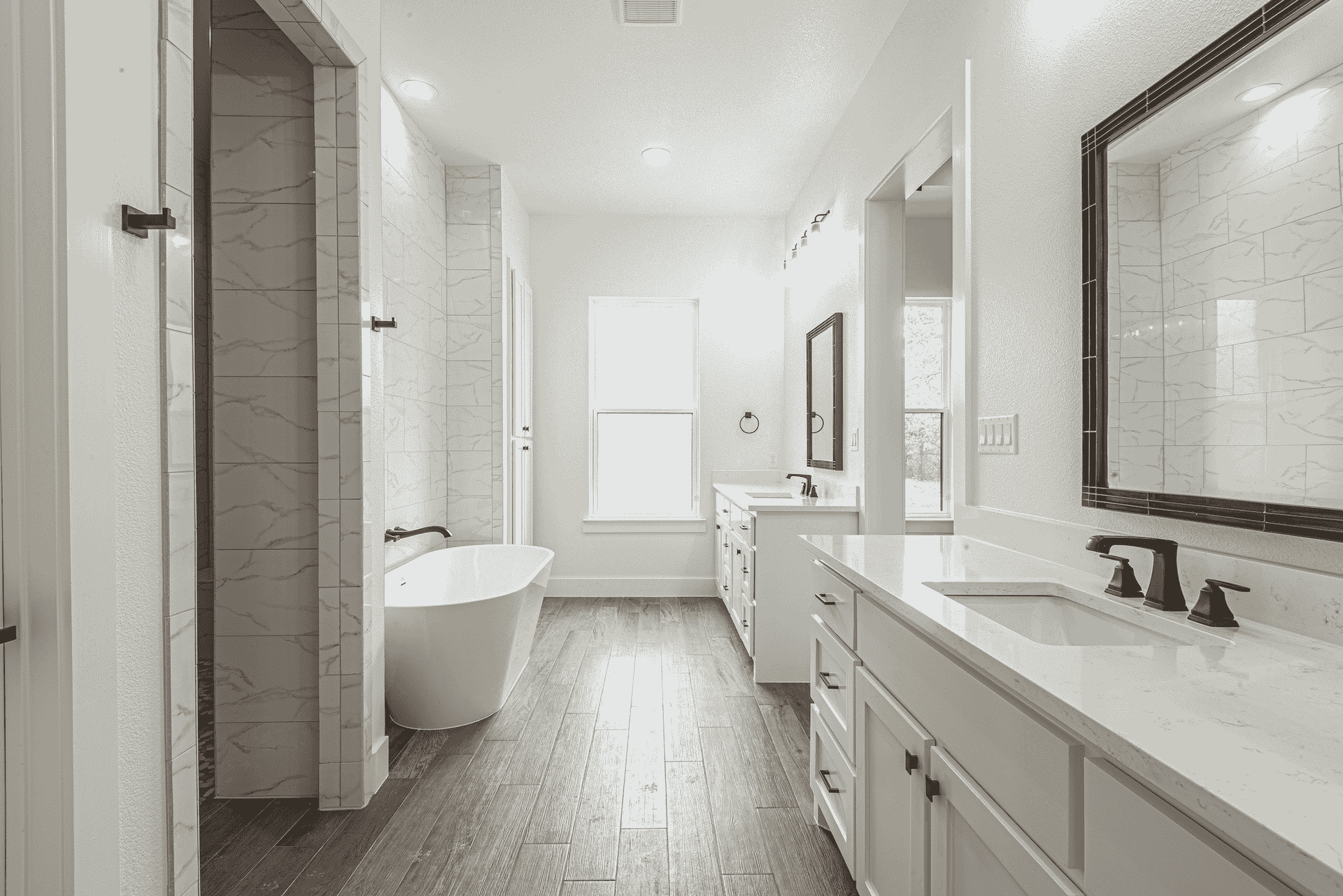 A bathroom with two sinks , a tub , and a mirror.