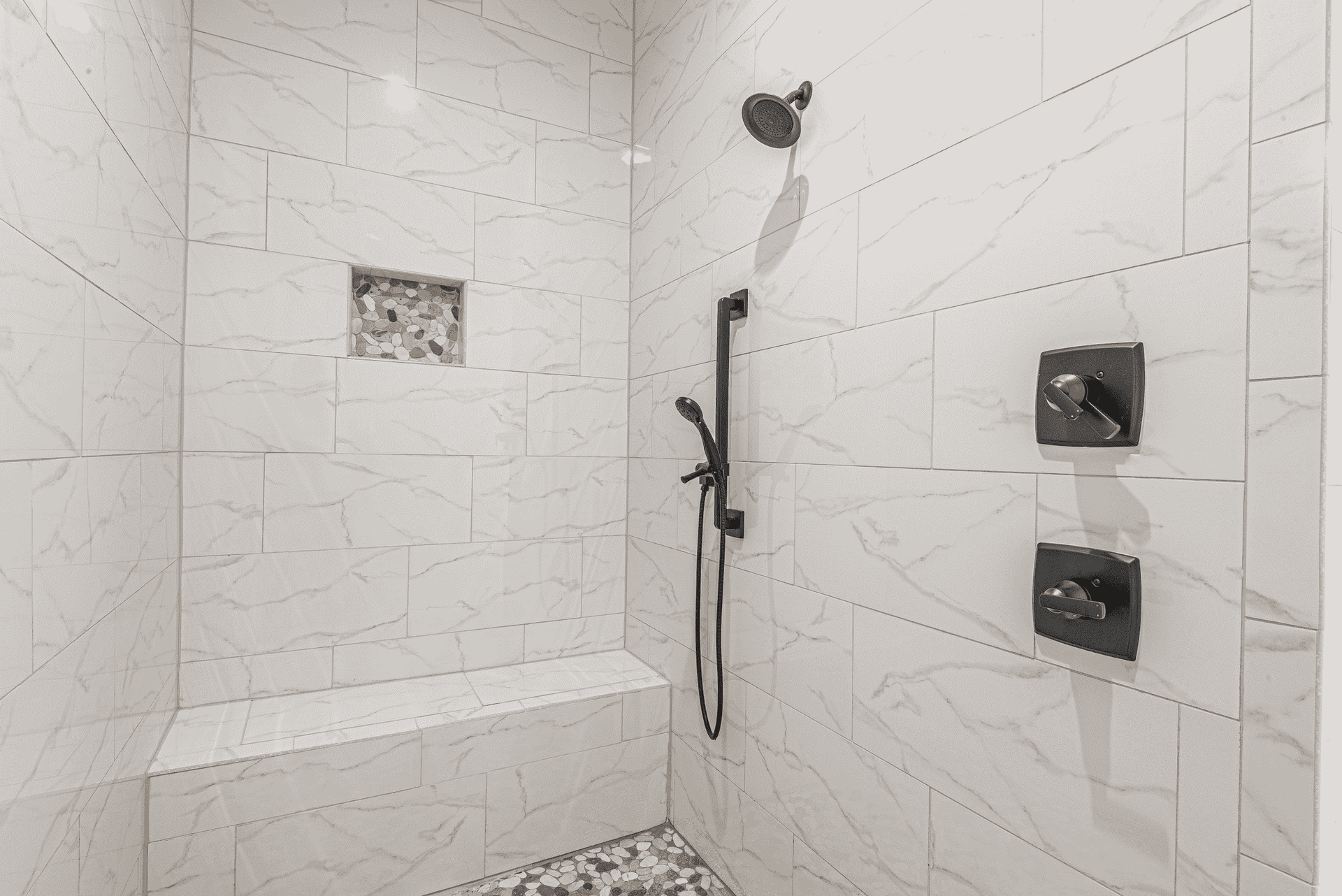 A shower with a bench and a shower head in a bathroom.