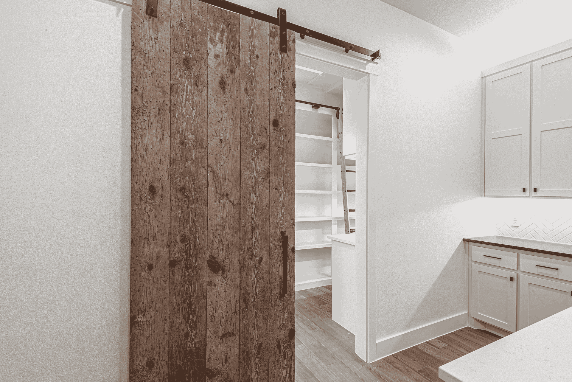 A black and white photo of a laundry room with a sliding barn door.