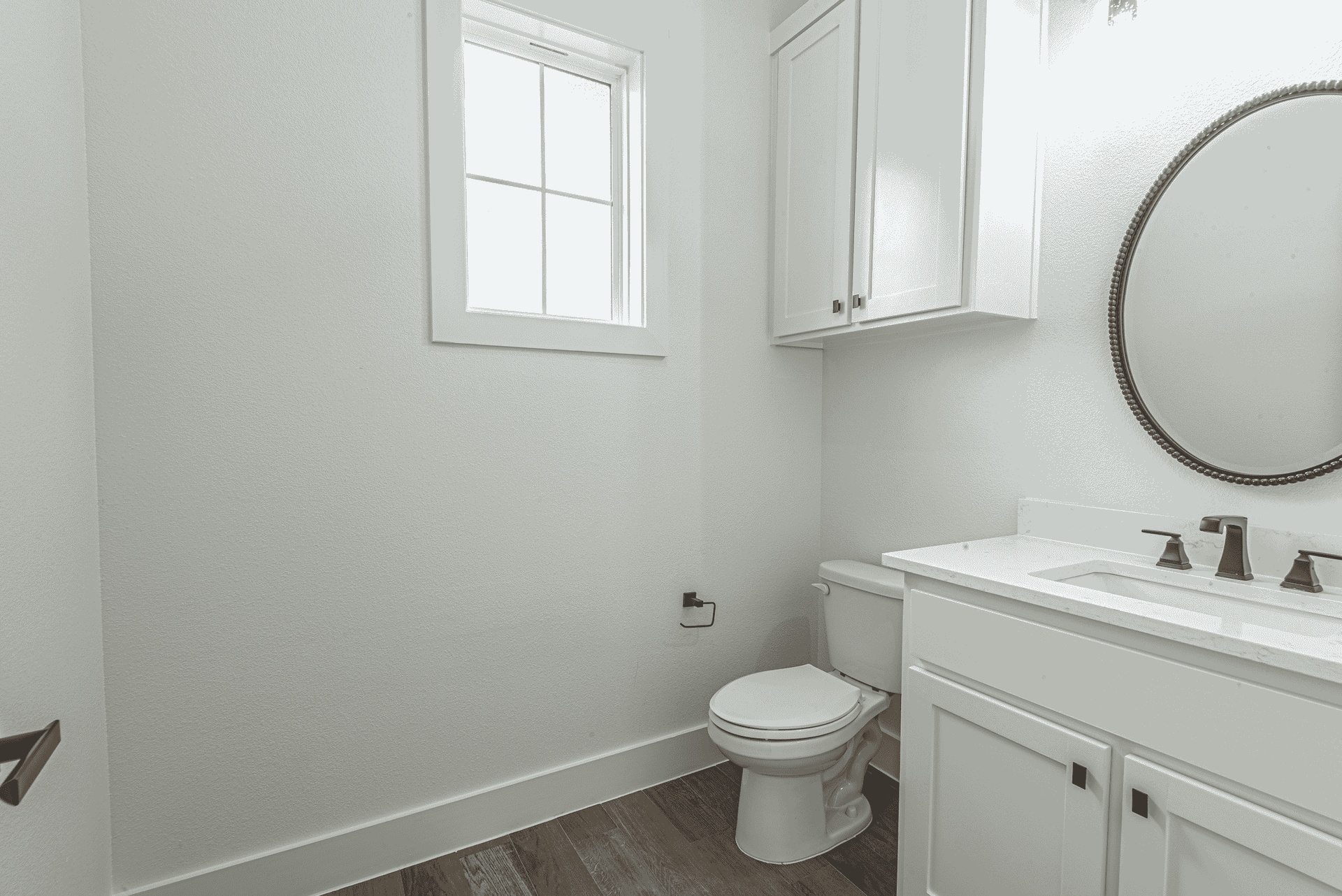 A bathroom with a toilet , sink , mirror and window.