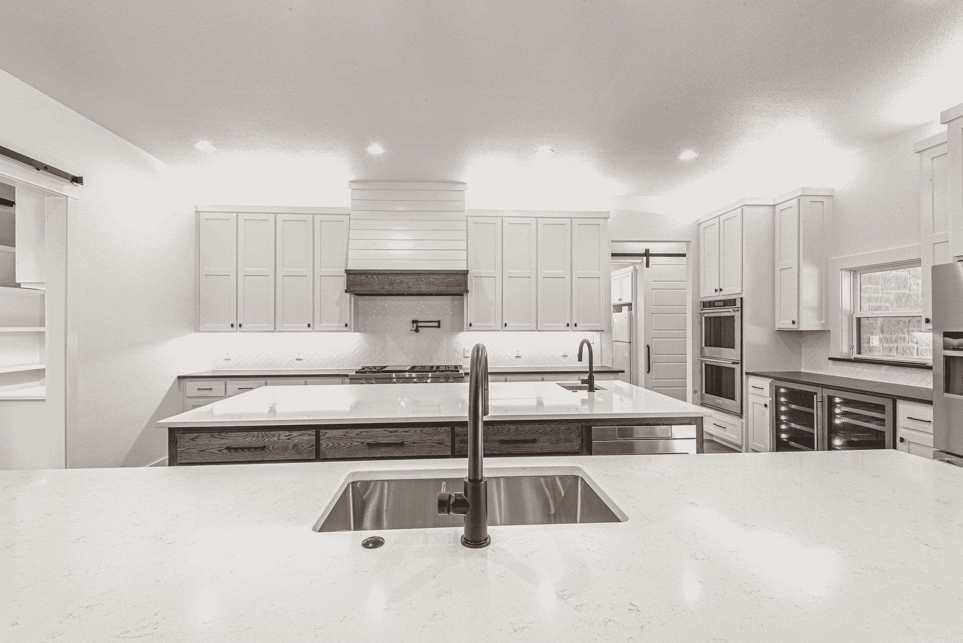 A black and white photo of a kitchen with a double sink.