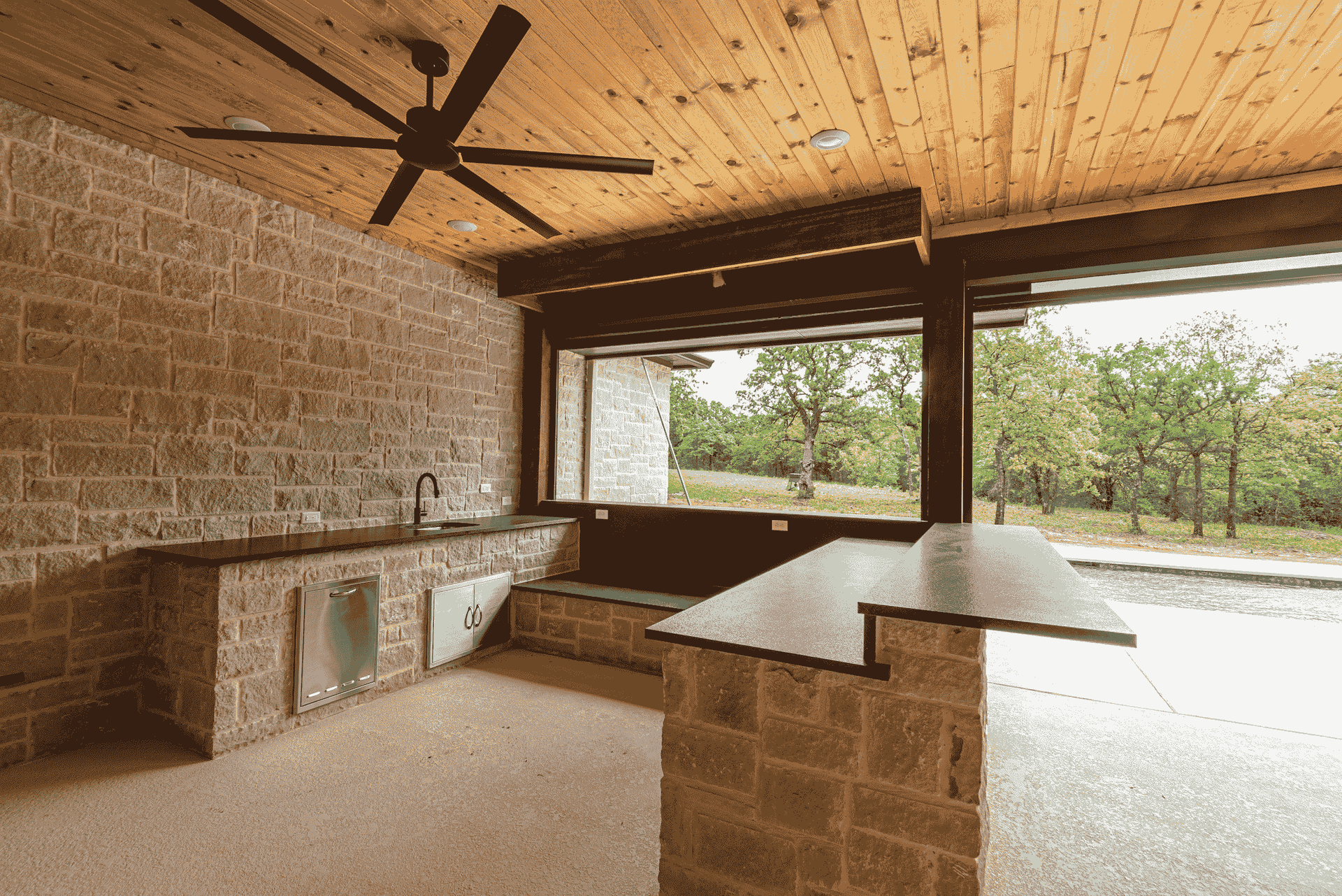 A kitchen with a ceiling fan and a large window.