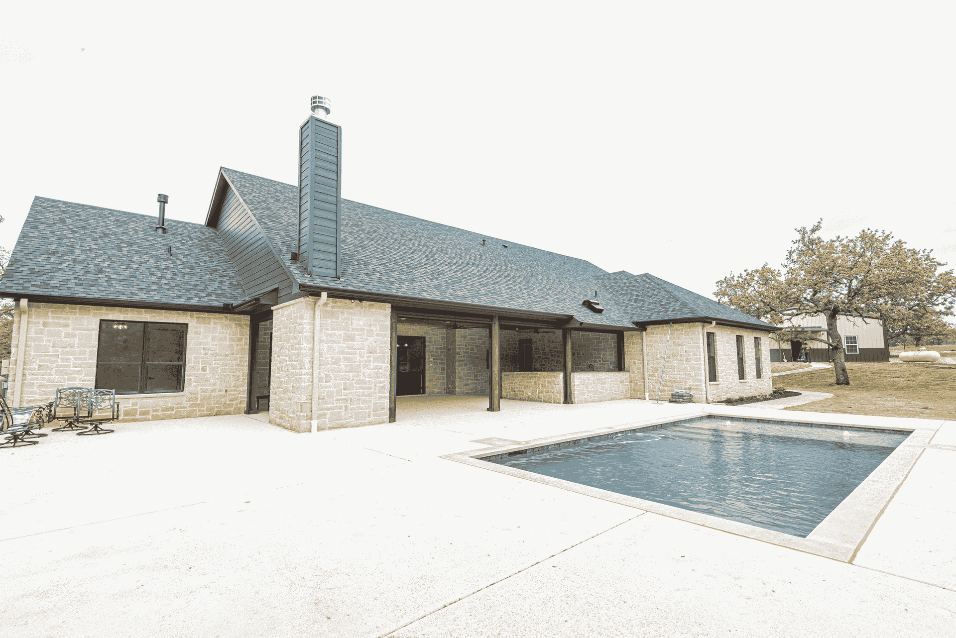 A large brick house with a large swimming pool in front of it.