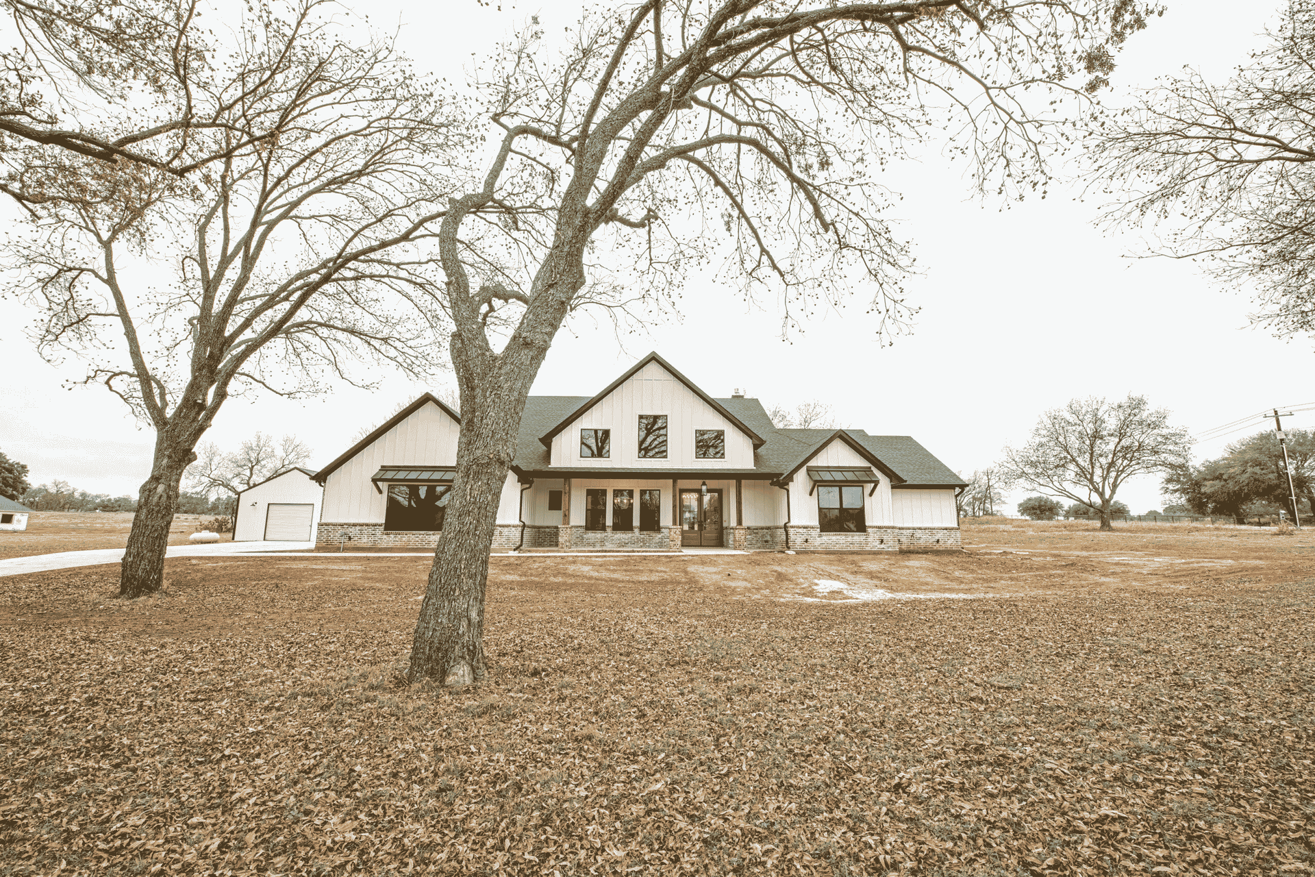 A house is sitting in the middle of a field with trees in front of it.