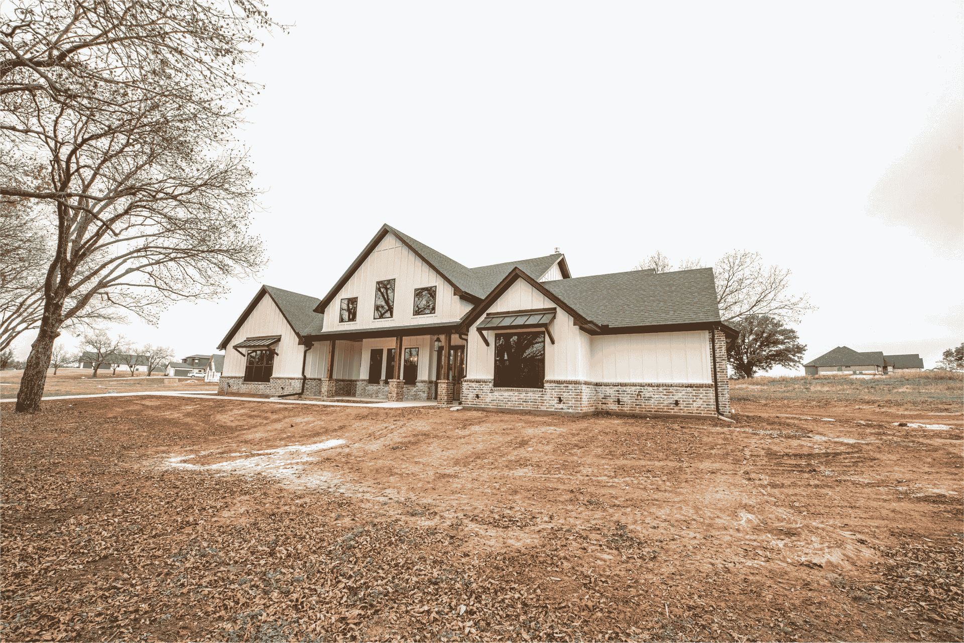 A large house is sitting in the middle of a dirt field.
