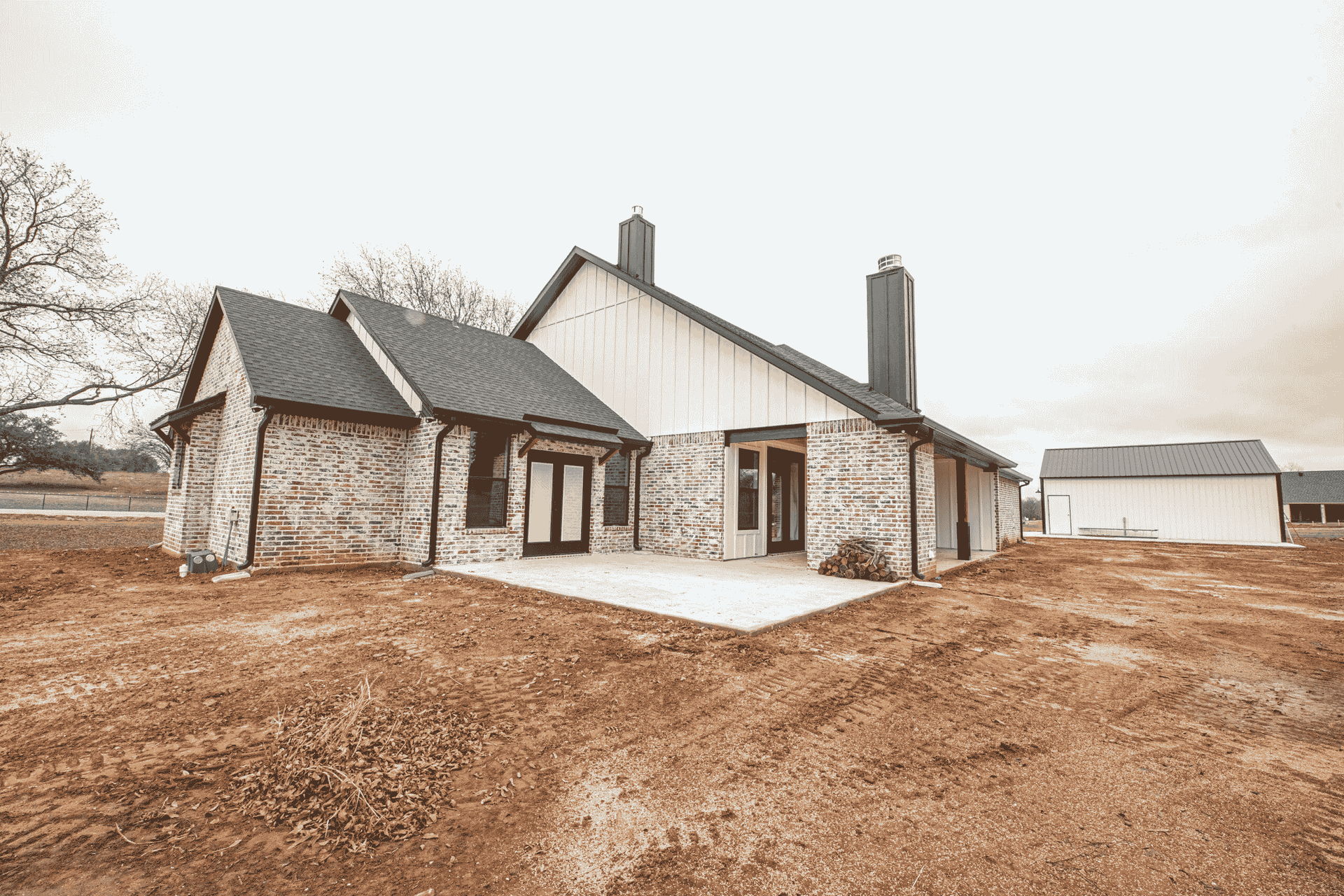 A black and white photo of a brick house in a dirt field.