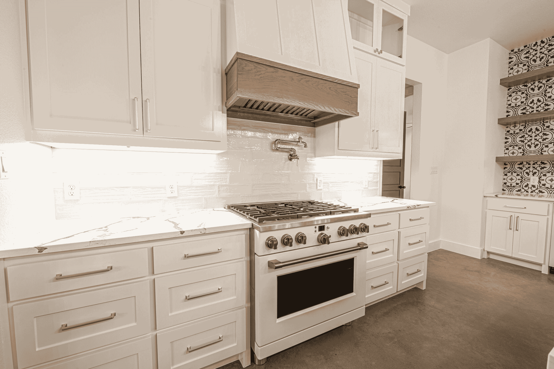A kitchen with white cabinets , a stove , and a sink.