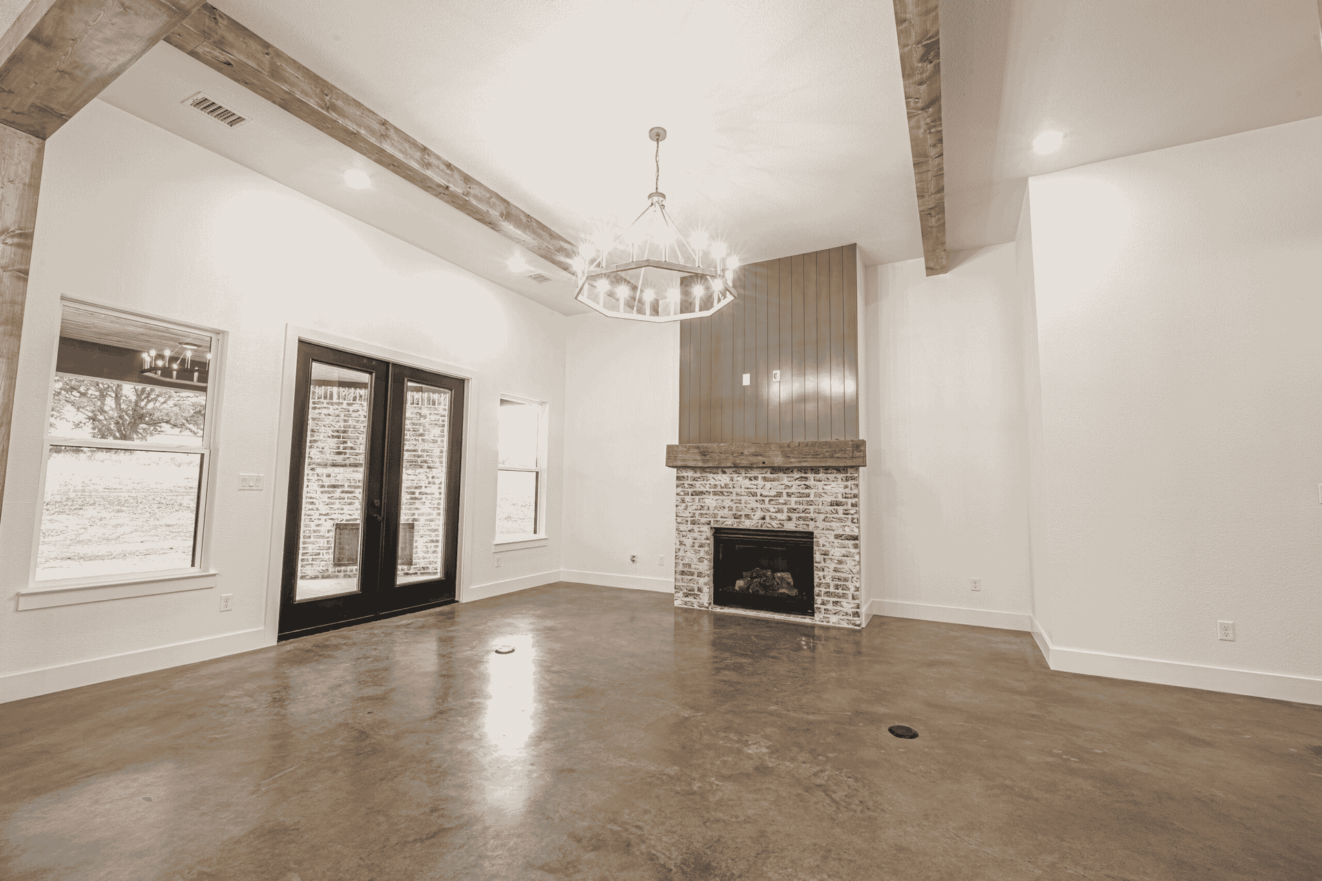 An empty living room with a fireplace and a chandelier.