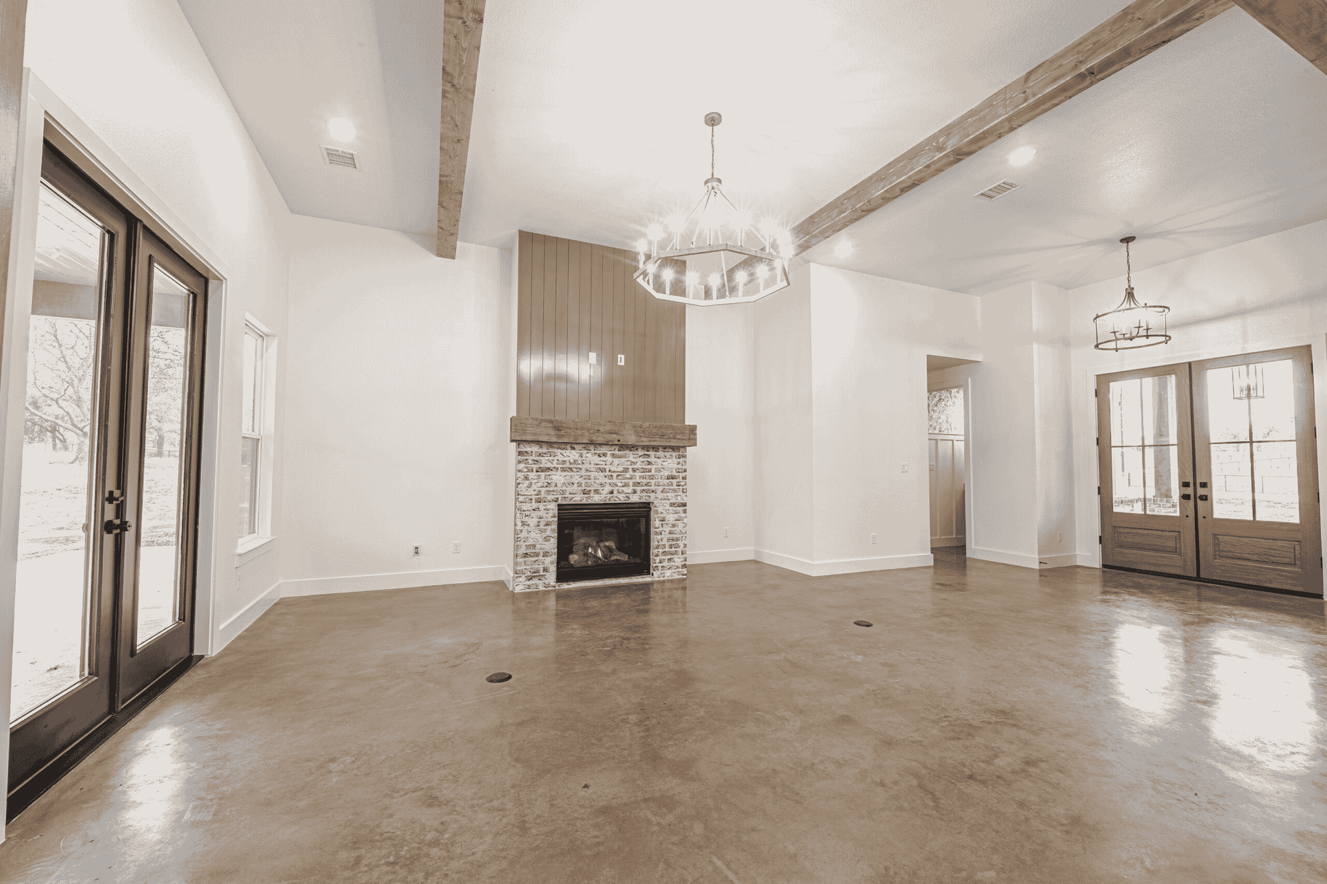 An empty living room with a fireplace and a chandelier.