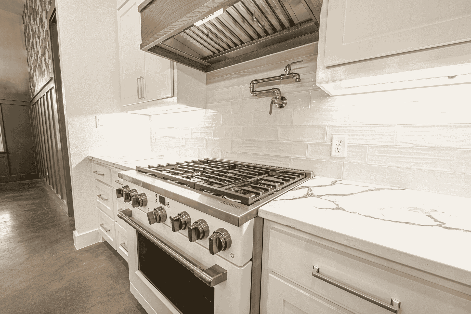 A black and white photo of a kitchen with a stove top oven.