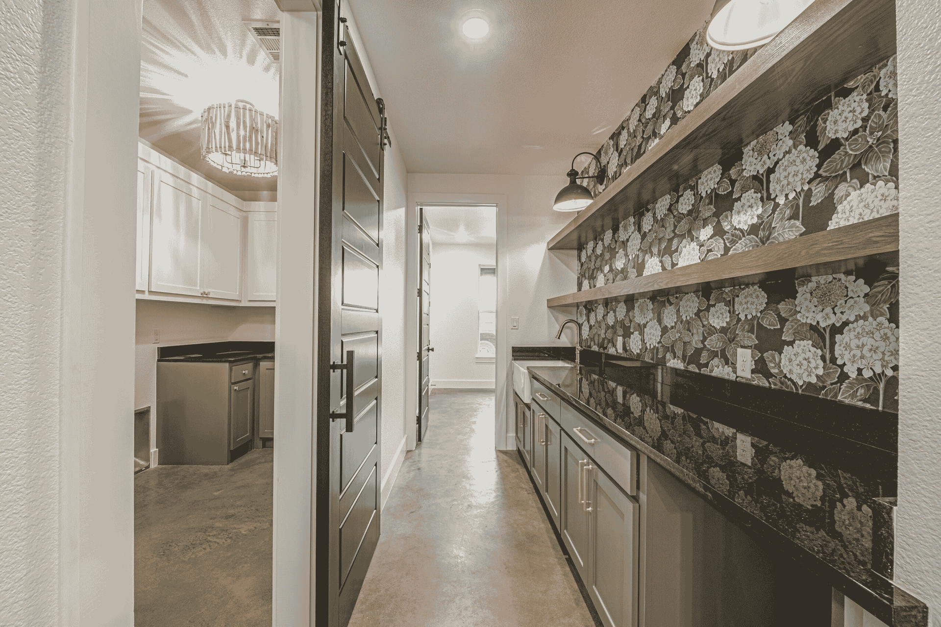 A long hallway leading to a kitchen with a floral wallpaper on the wall.