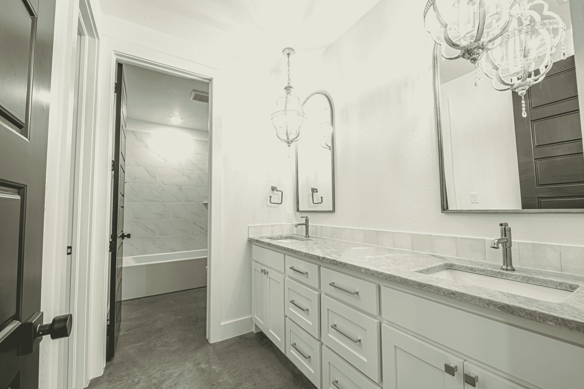 A bathroom with two sinks , a mirror and a chandelier.