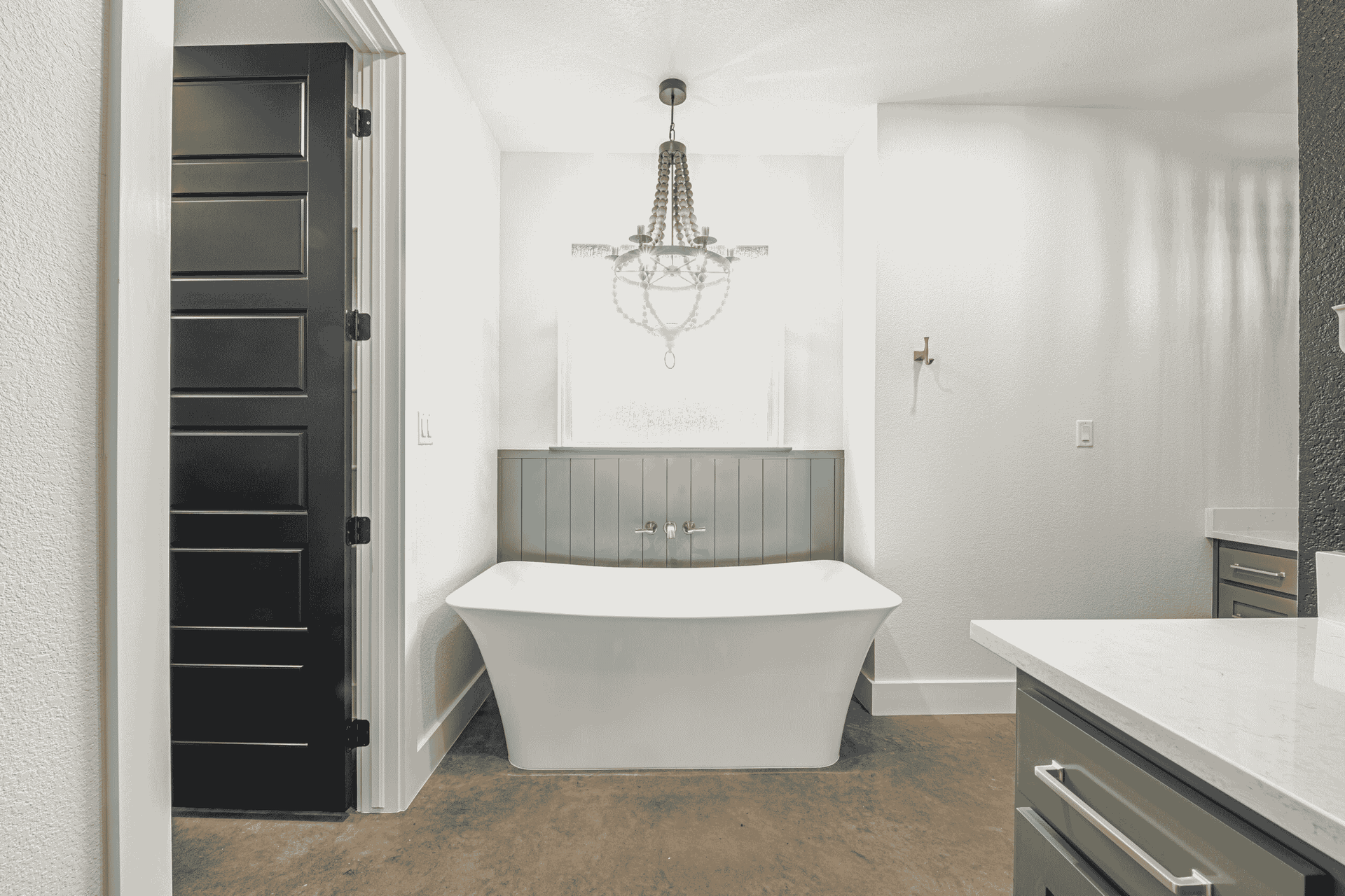 A bathroom with a bathtub , sink , mirror and chandelier.