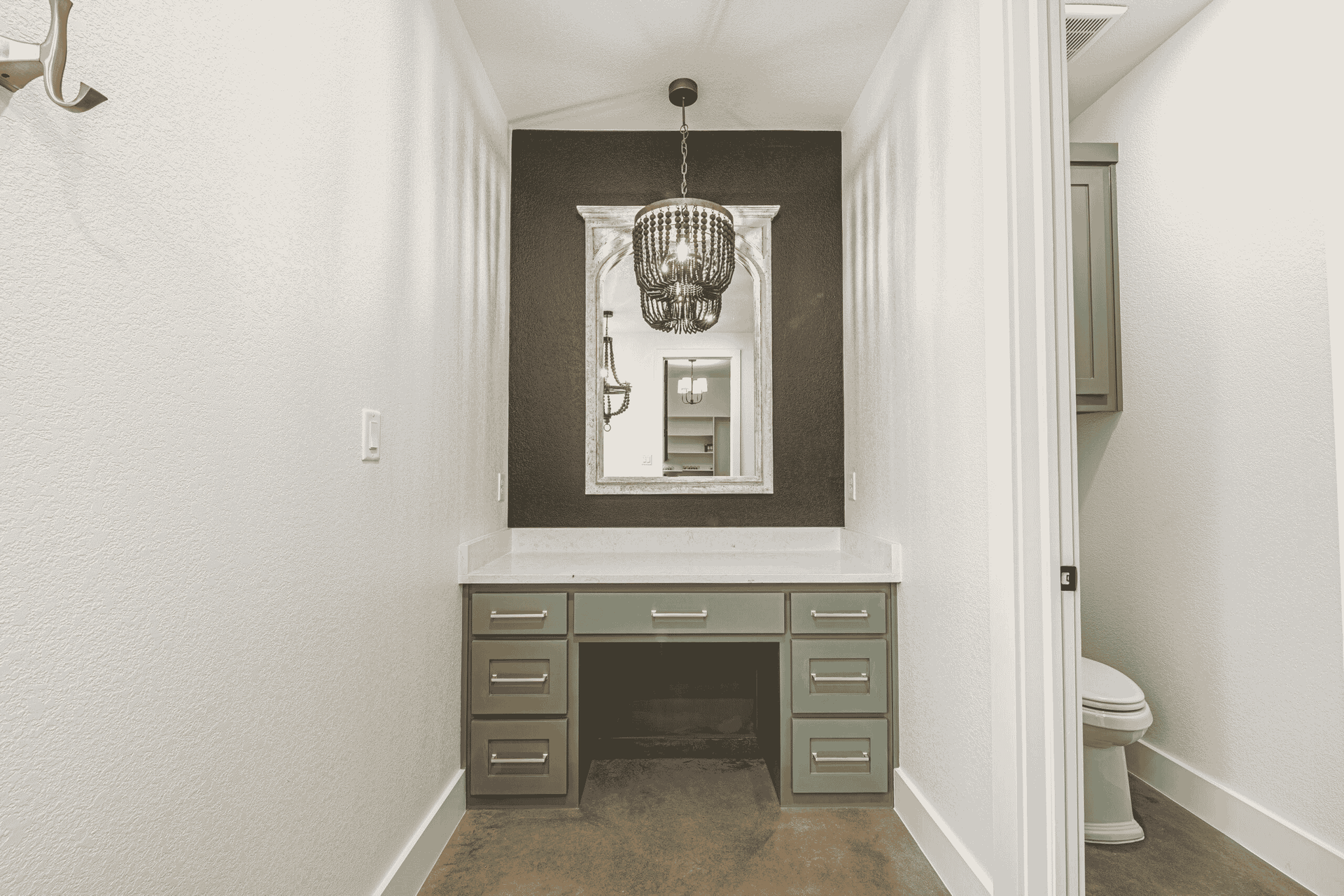 A bathroom with a desk , mirror and toilet.