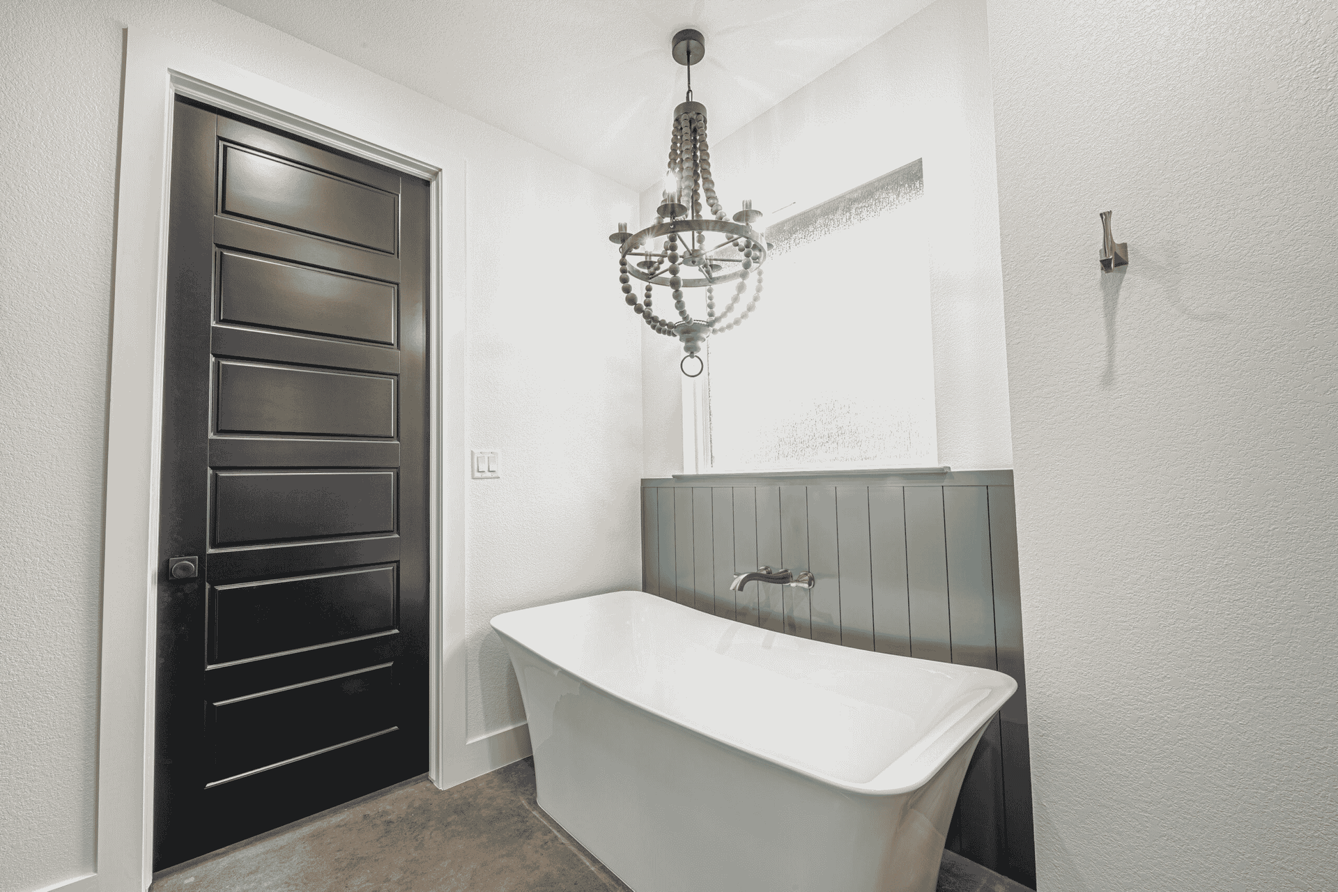A bathroom with a bathtub and a chandelier hanging from the ceiling.