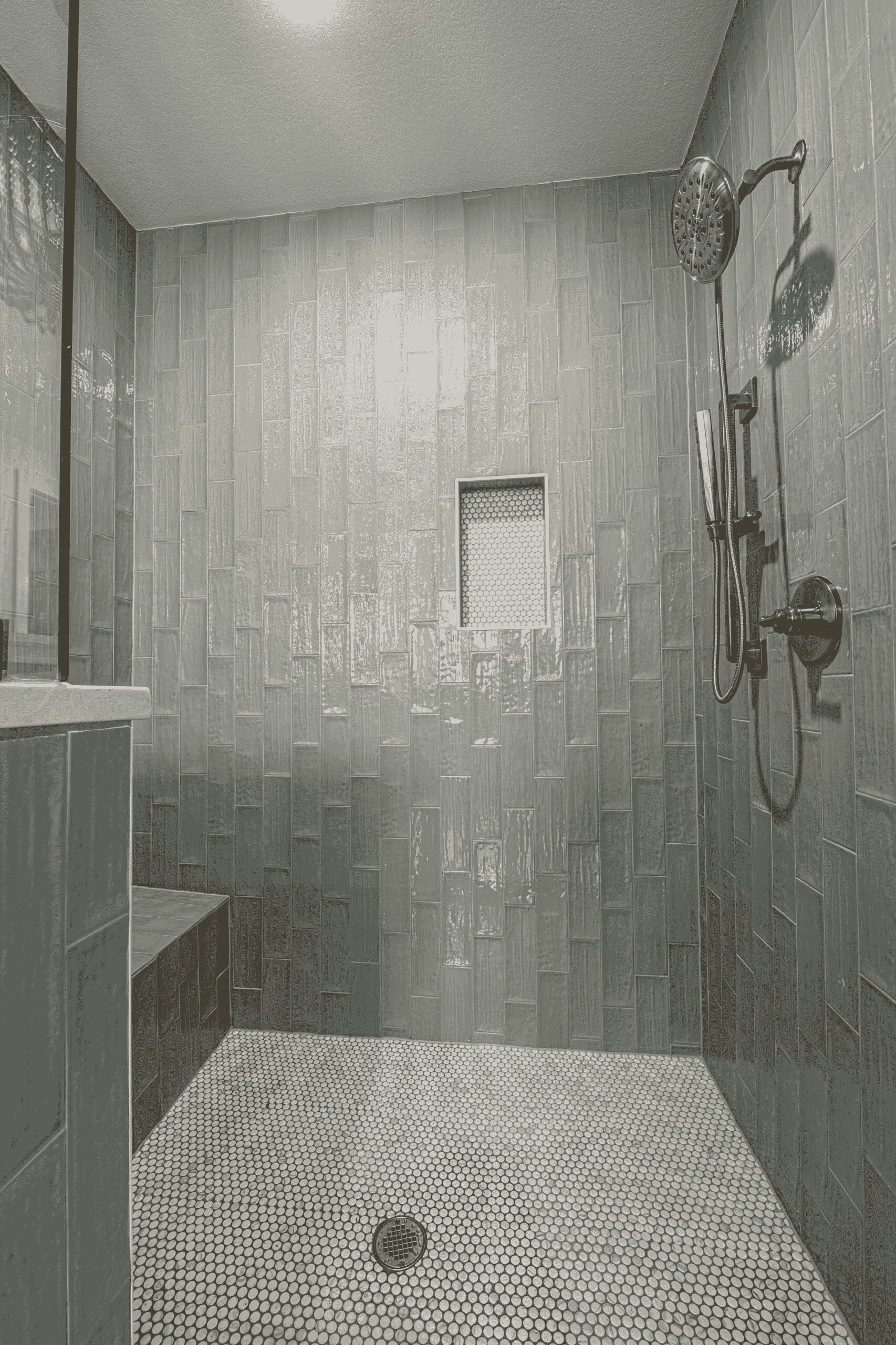 A black and white photo of a bathroom with a walk in shower.