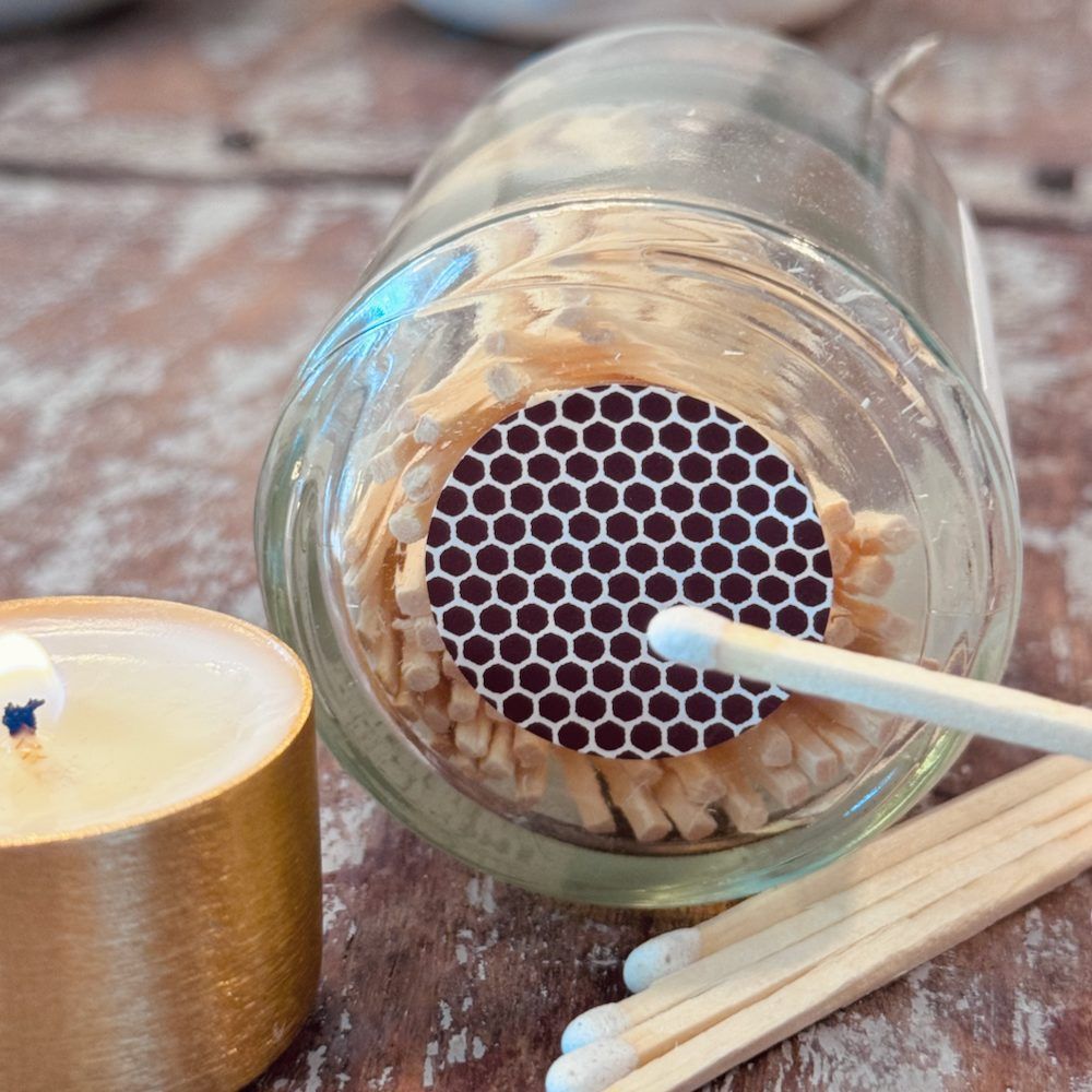 Bouteille en verre d'allumettes étiquetée « Make a Wish » avec bouchon, nœud et bougie allumée.