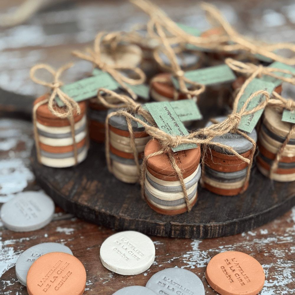 Petites piles de disques d'argile colorés attachés avec de la ficelle, chacun avec une étiquette, sur une planche de bois.
