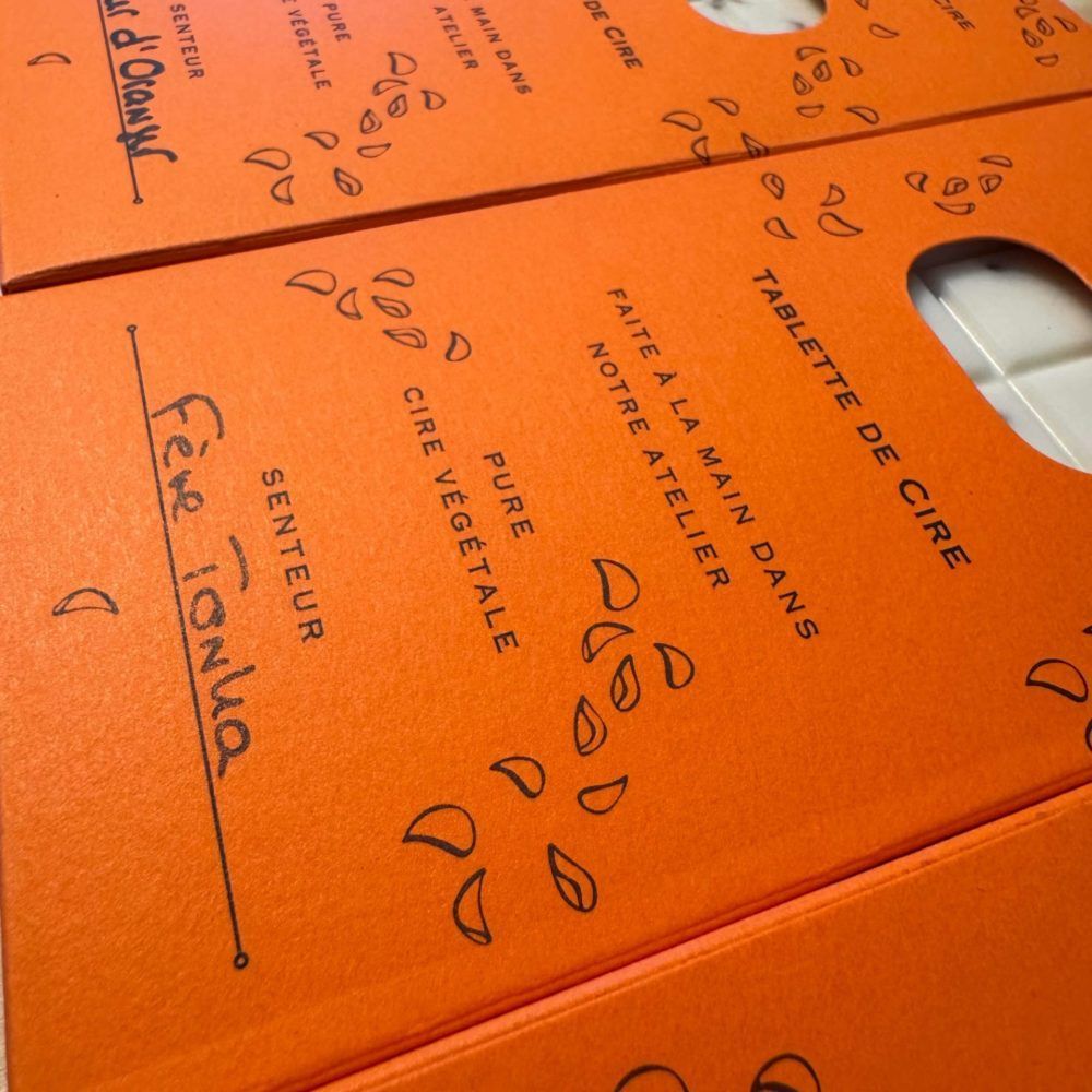 Emballage produit orange avec texte, incluant le parfum 