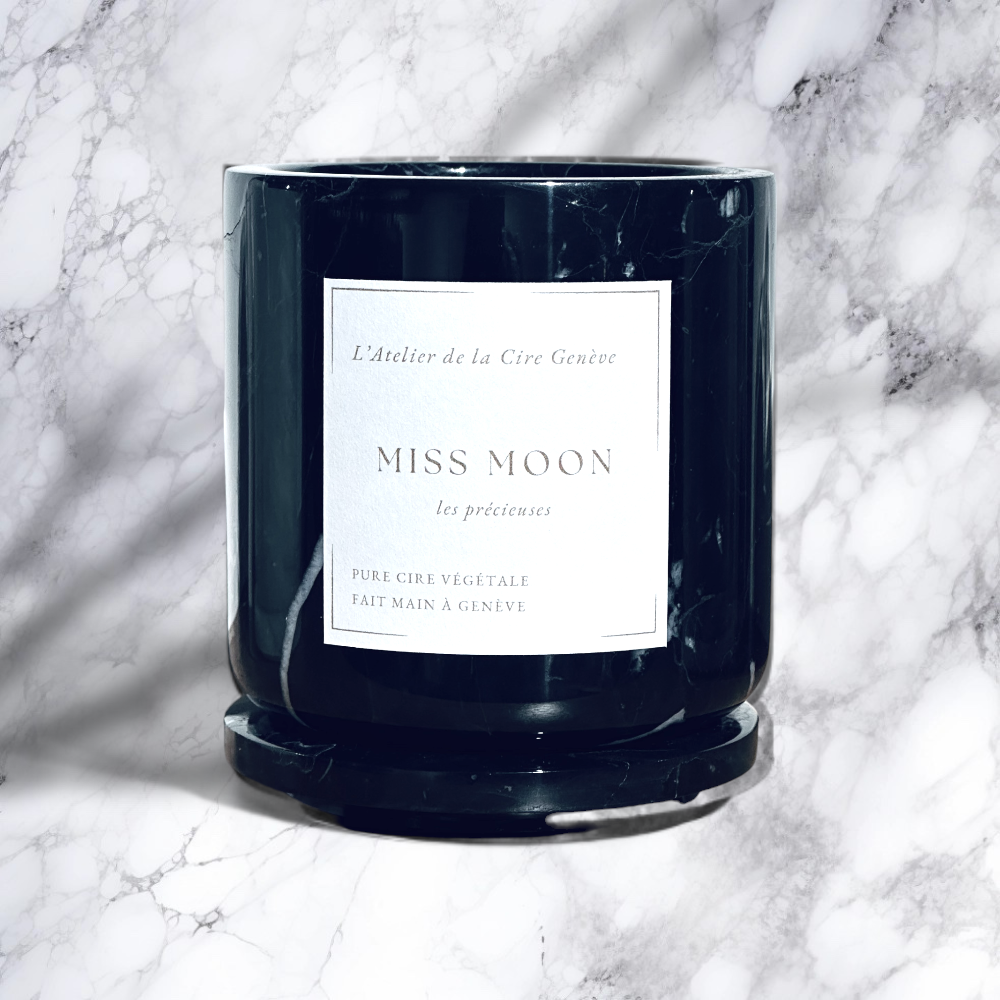 Bougie en marbre noir avec une étiquette blanche indiquant « Miss Moon » sur une surface en marbre.
