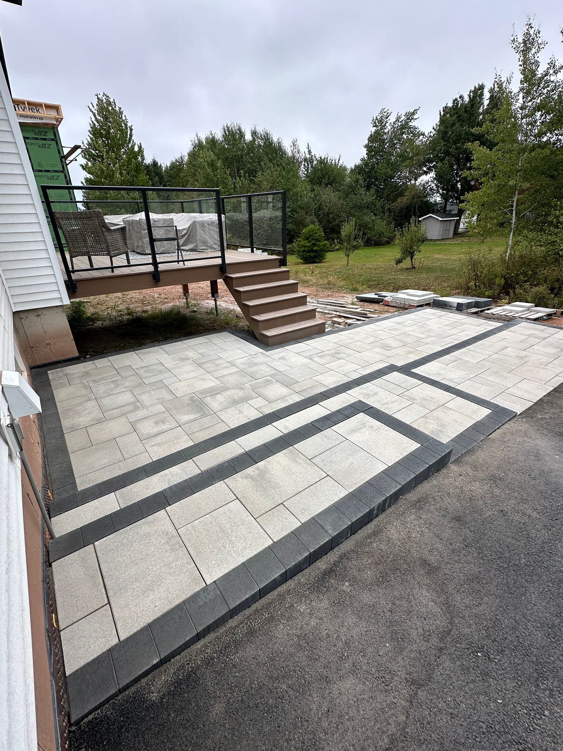 A patio with a deck and stairs is being built in front of a house.