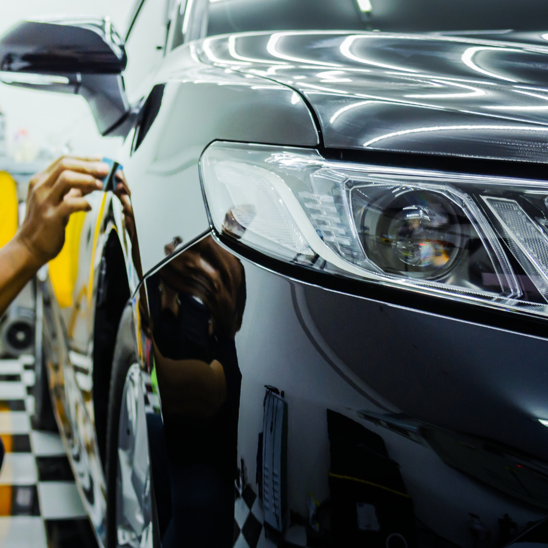 A person is polishing a black car in a garage
