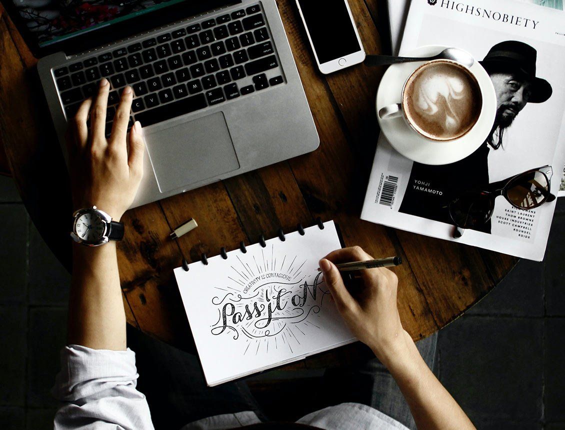 A person is sitting at a table with a laptop and a cup of coffee.