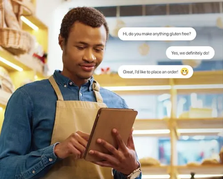 Person holding tablet with apron in store chatting online with customer A man in an apron is using a tablet in a bakery.