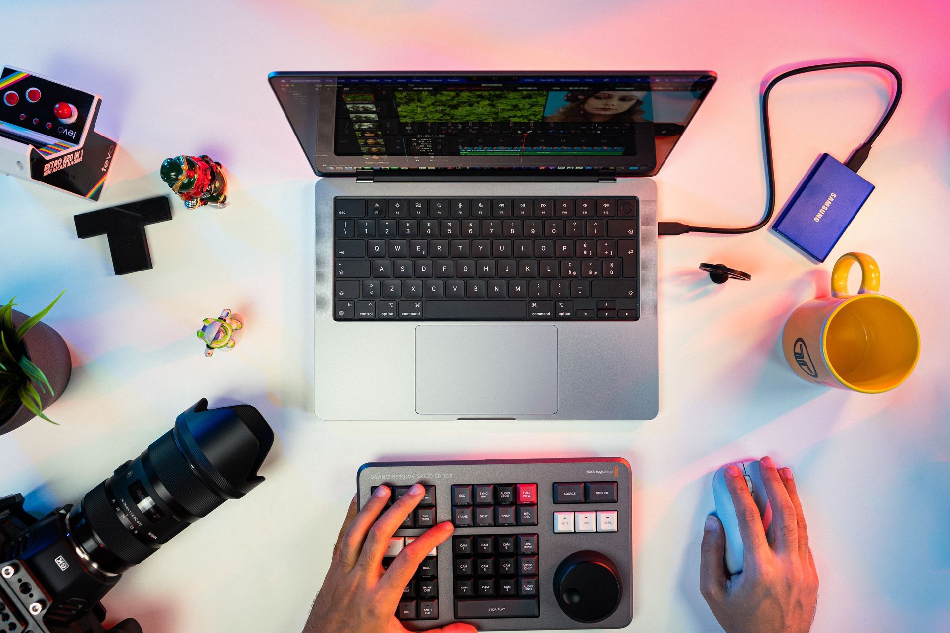 Laptop and video editing setup with hands on keyboard and editing panel.