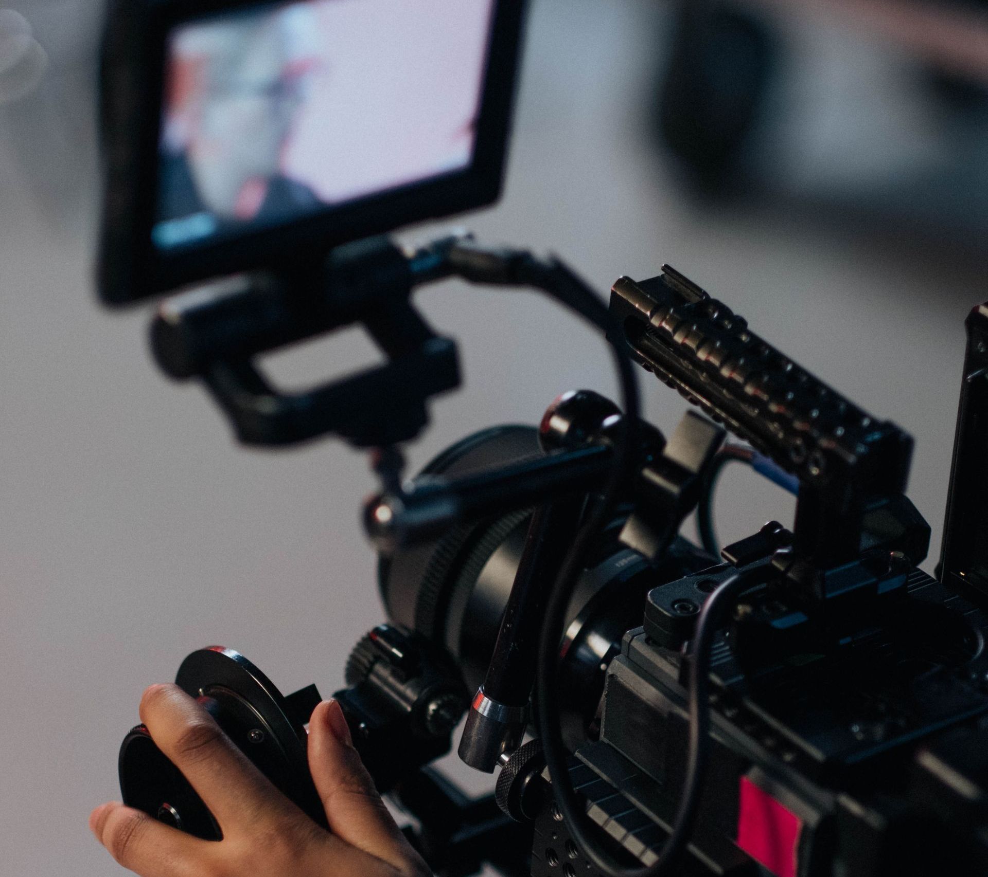 A person is holding a video camera with a monitor attached to it.