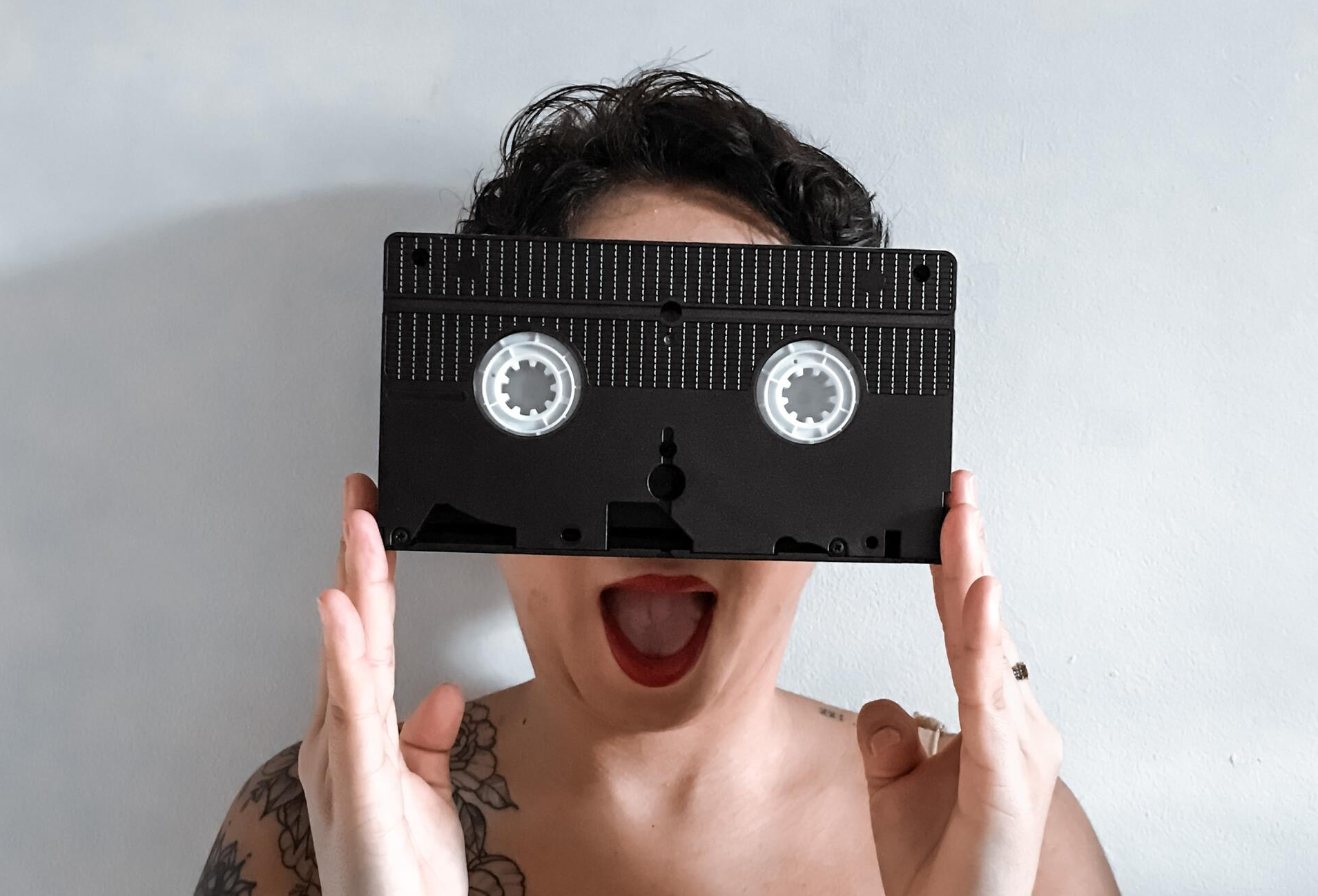 A woman is holding a video tape in front of her face