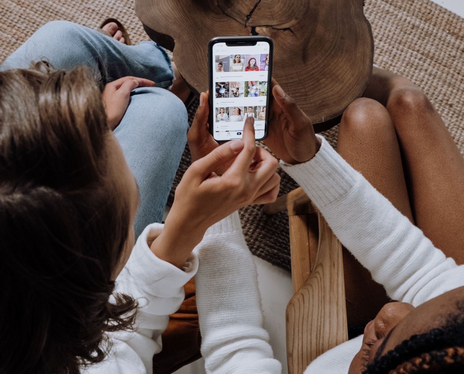 A group of people are sitting on the floor looking at a cell phone.