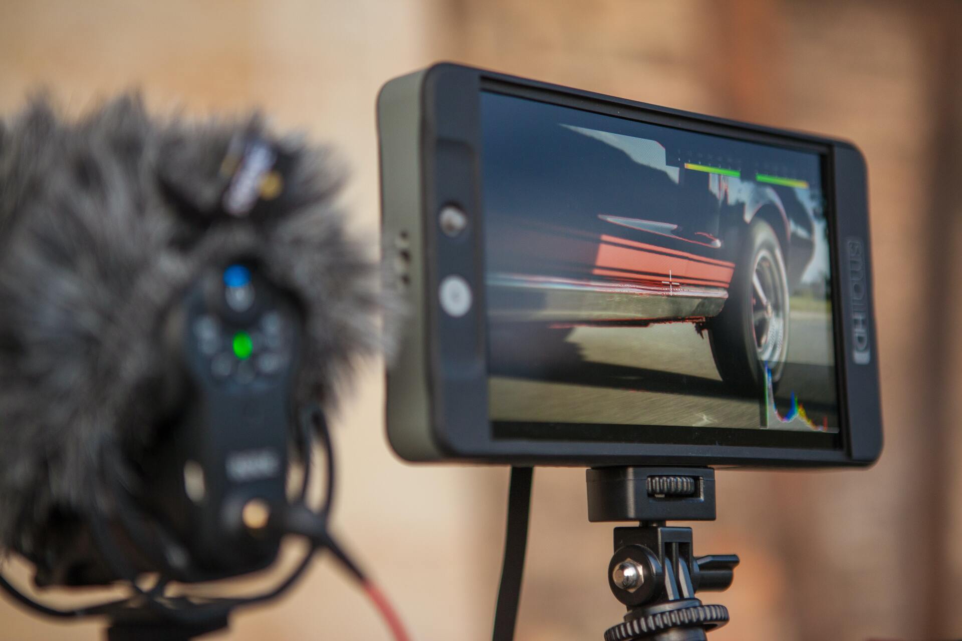 close up image of on board video monitor on top of dslr cinema video camera A cell phone is sitting on a tripod next to a microphone.