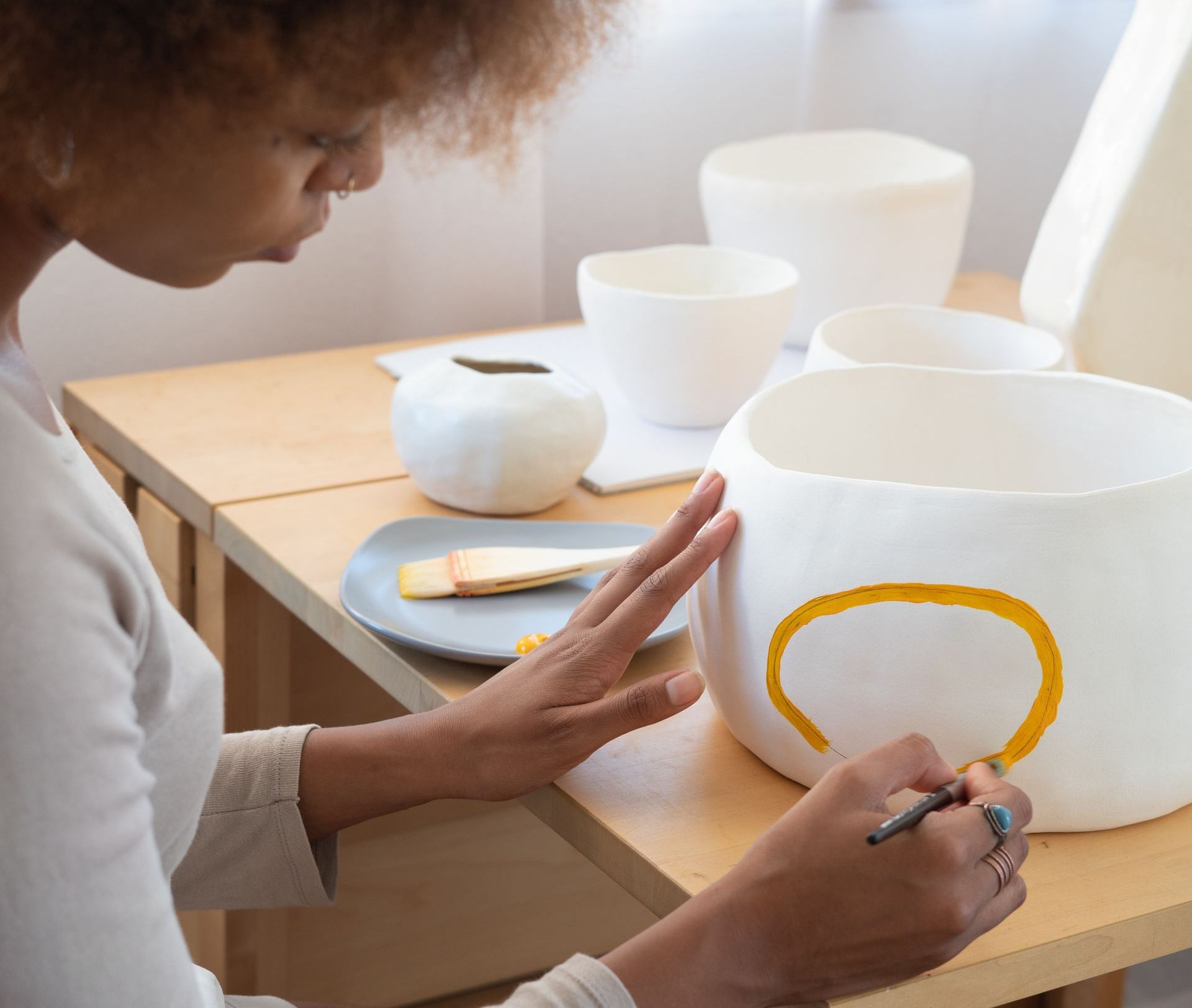 A woman is drawing a yellow circle on a white bowl